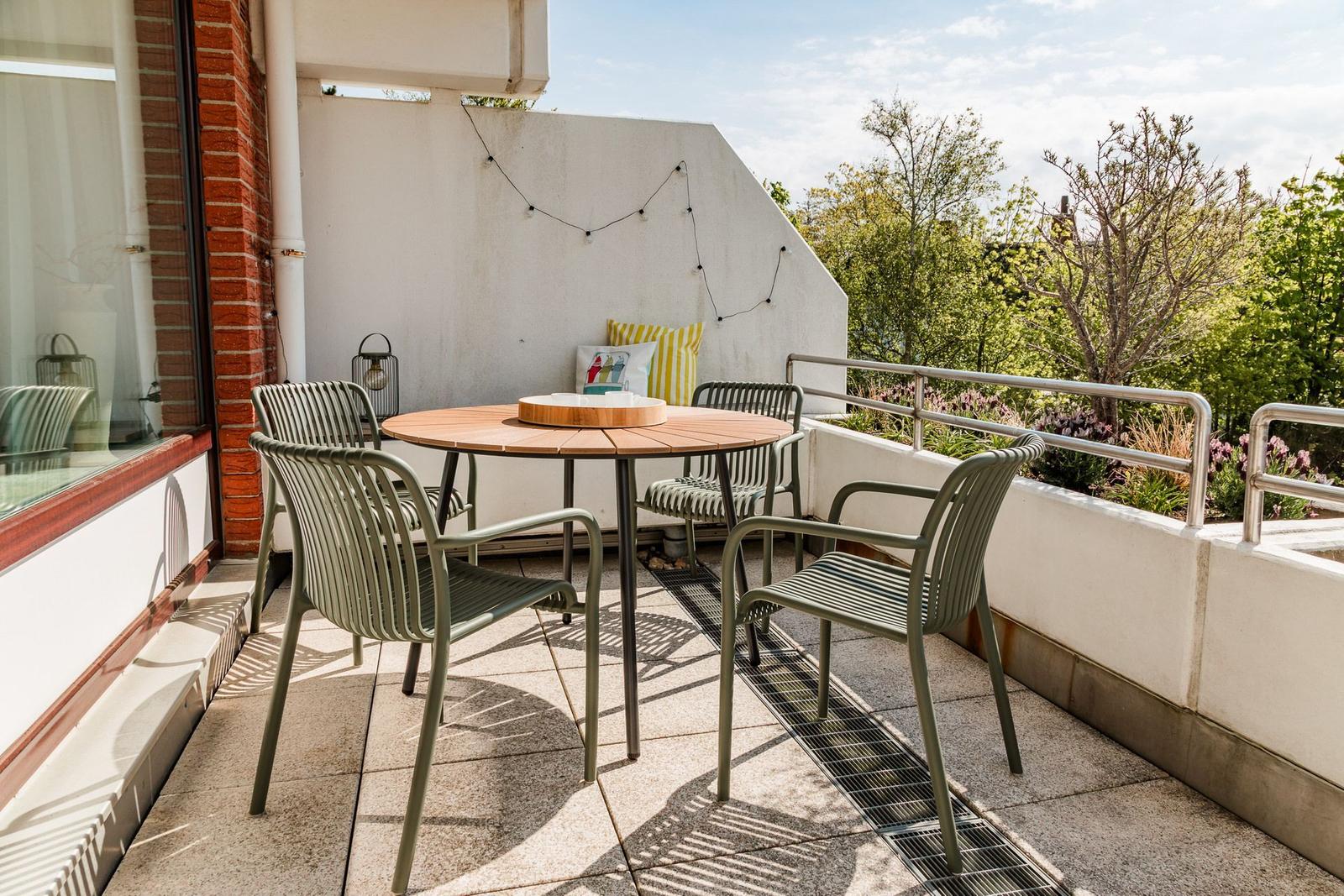 Terrace with round table and four chairs, view of green trees
