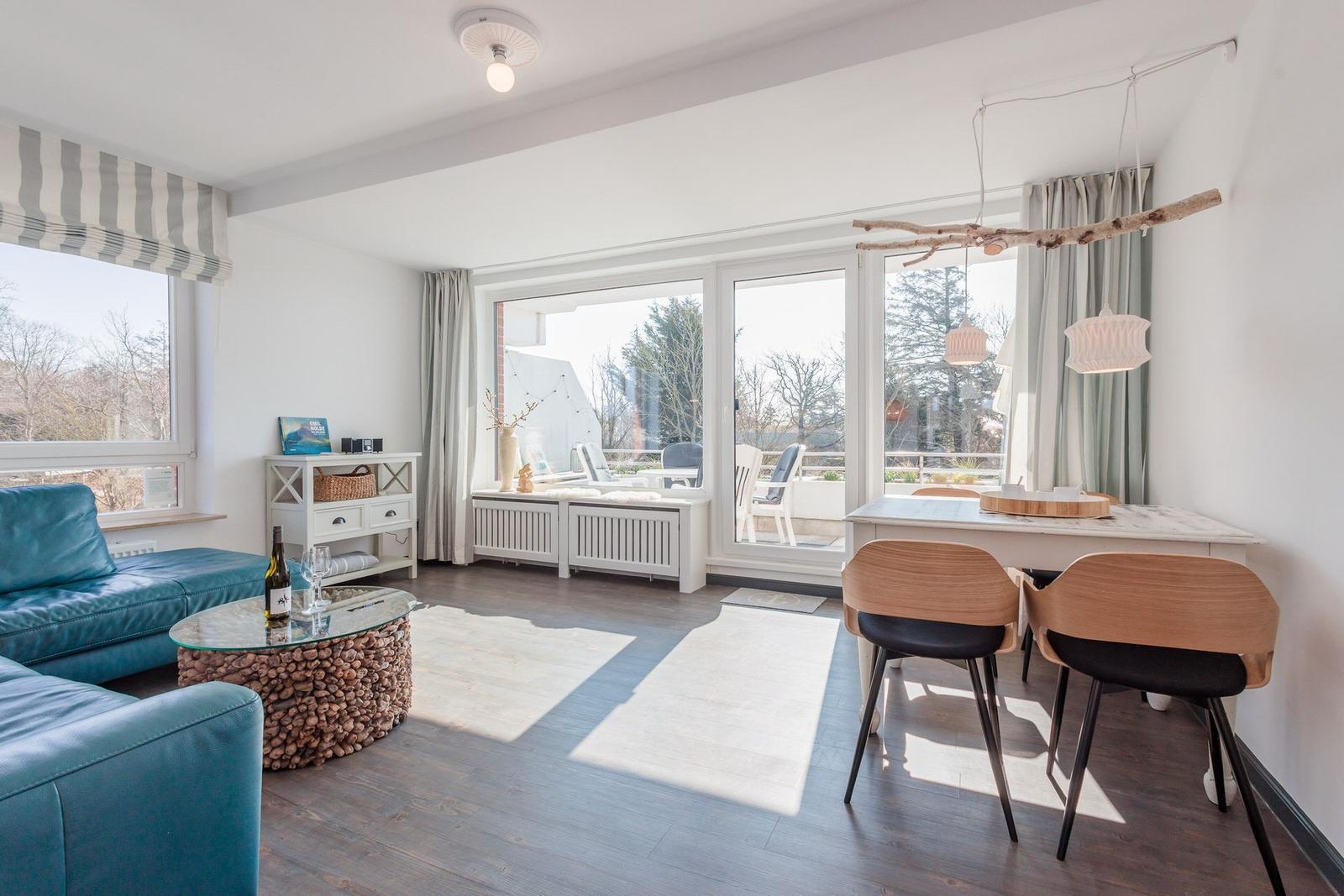 Living and dining area with blue sofa, glass table, and view of balcony.