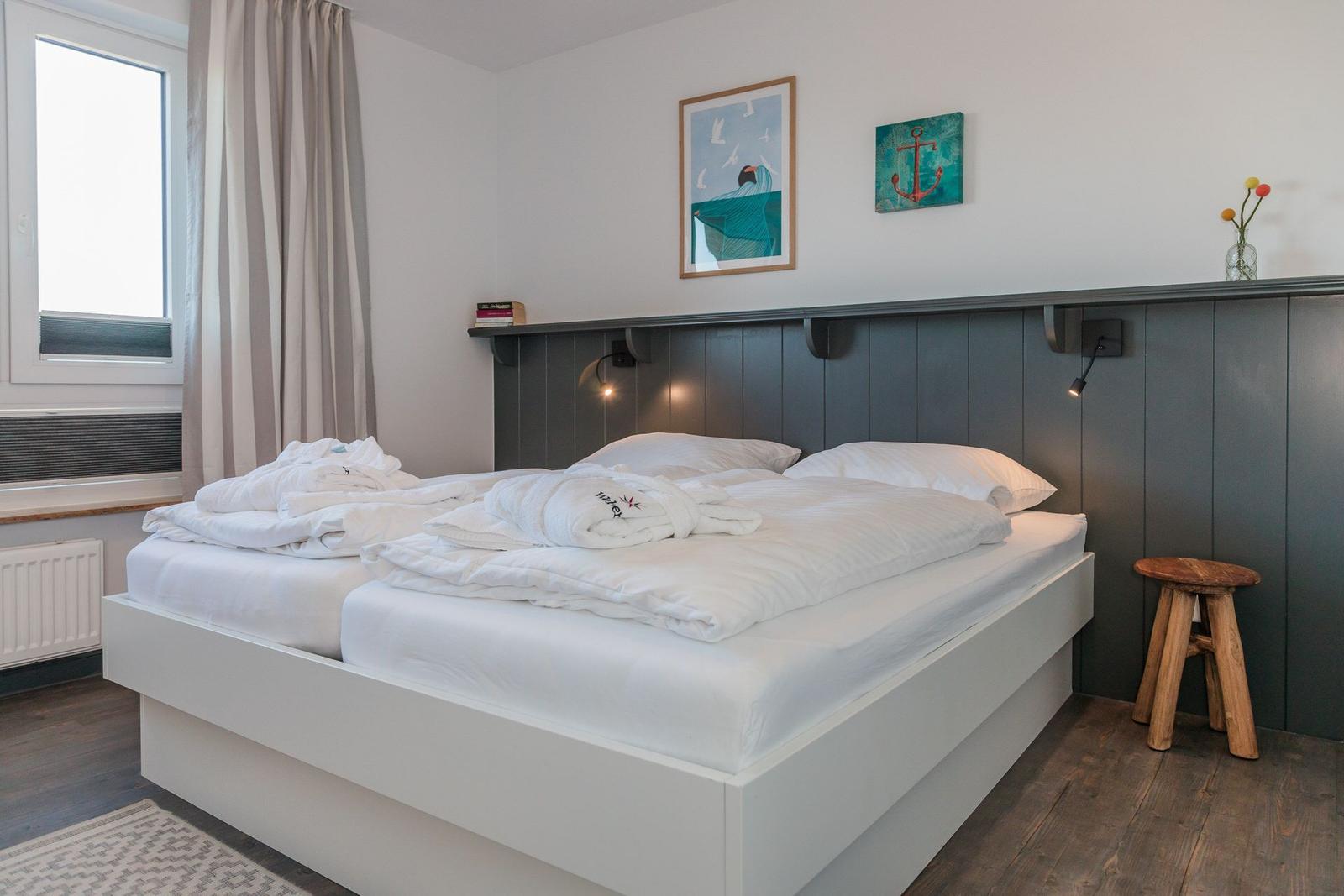 Bedroom with double bed, wall art, and wooden stool.