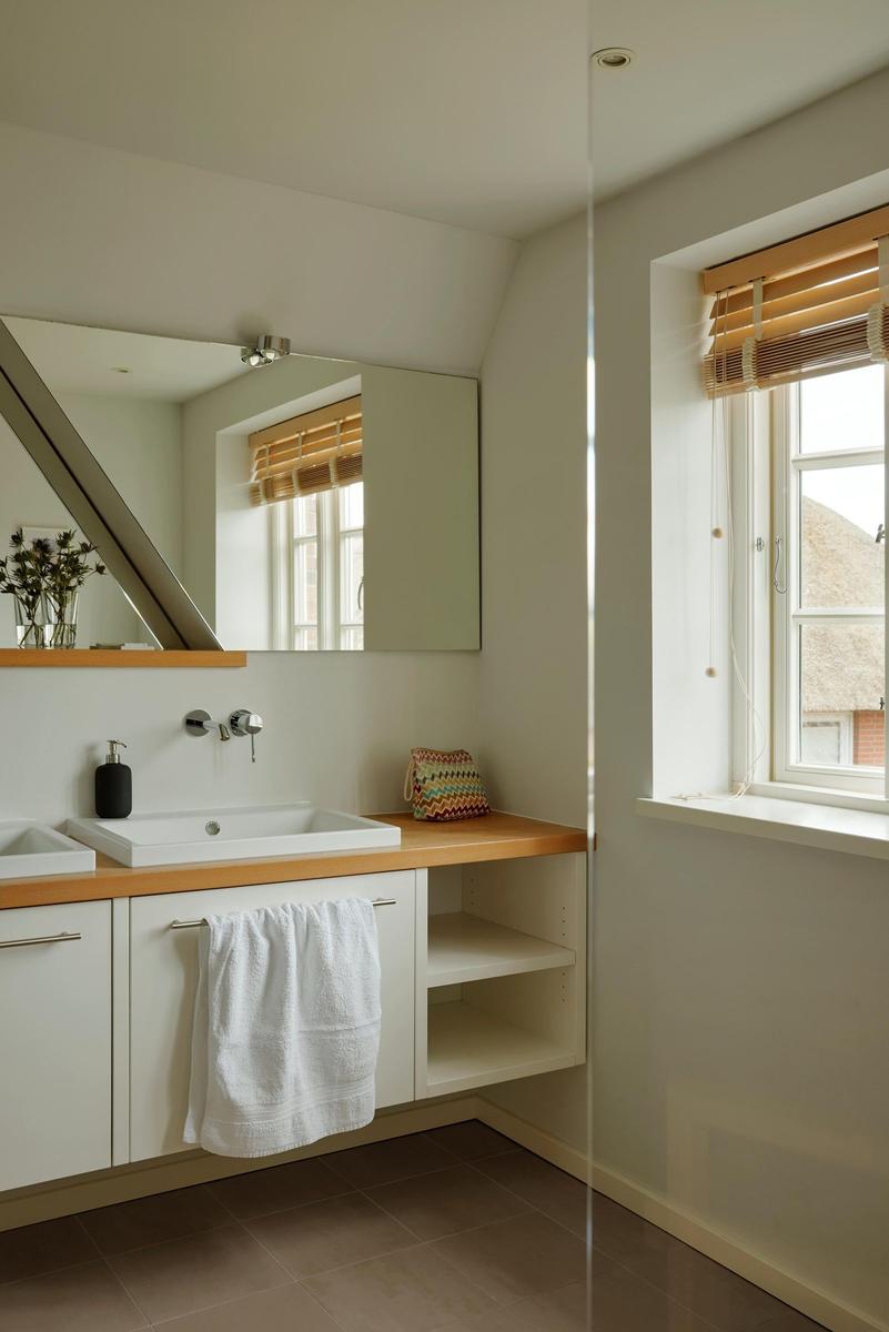 Bad mit Waschbecken, Spiegel und Fenster mit Jalousie