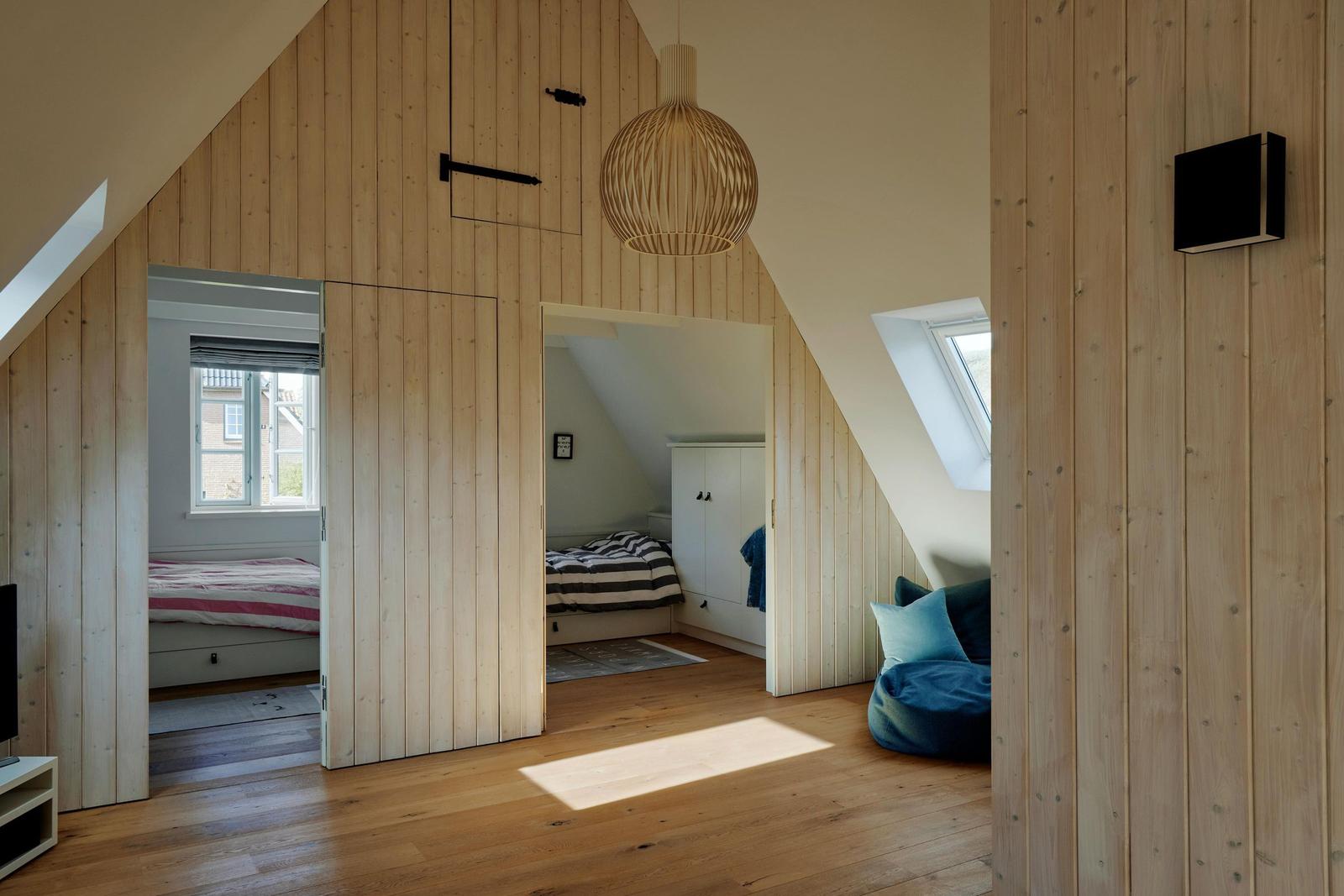 Dachgeschoss mit Holzwänden, zwei Schlafzimmern und Dachfenstern. Ein blauer Sitzbezug ist sichtbar.