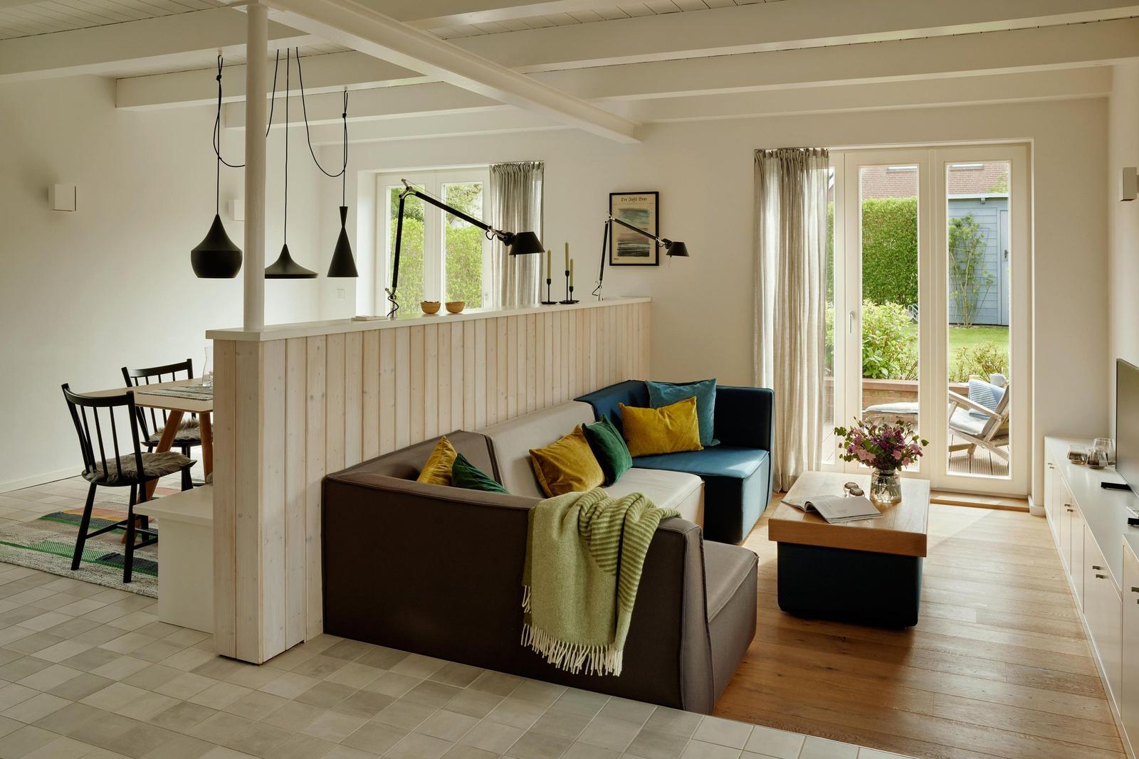 Wohn- und Essbereich mit Sofa, Tisch und Blick auf den Garten.