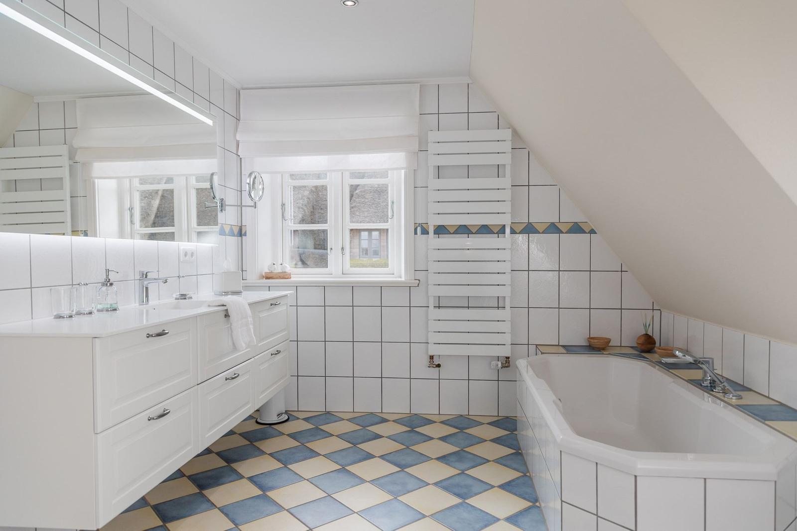 Badezimmer mit Dusche, Badewanne und Fenster. Fliesenboden und weiße Einrichtung.