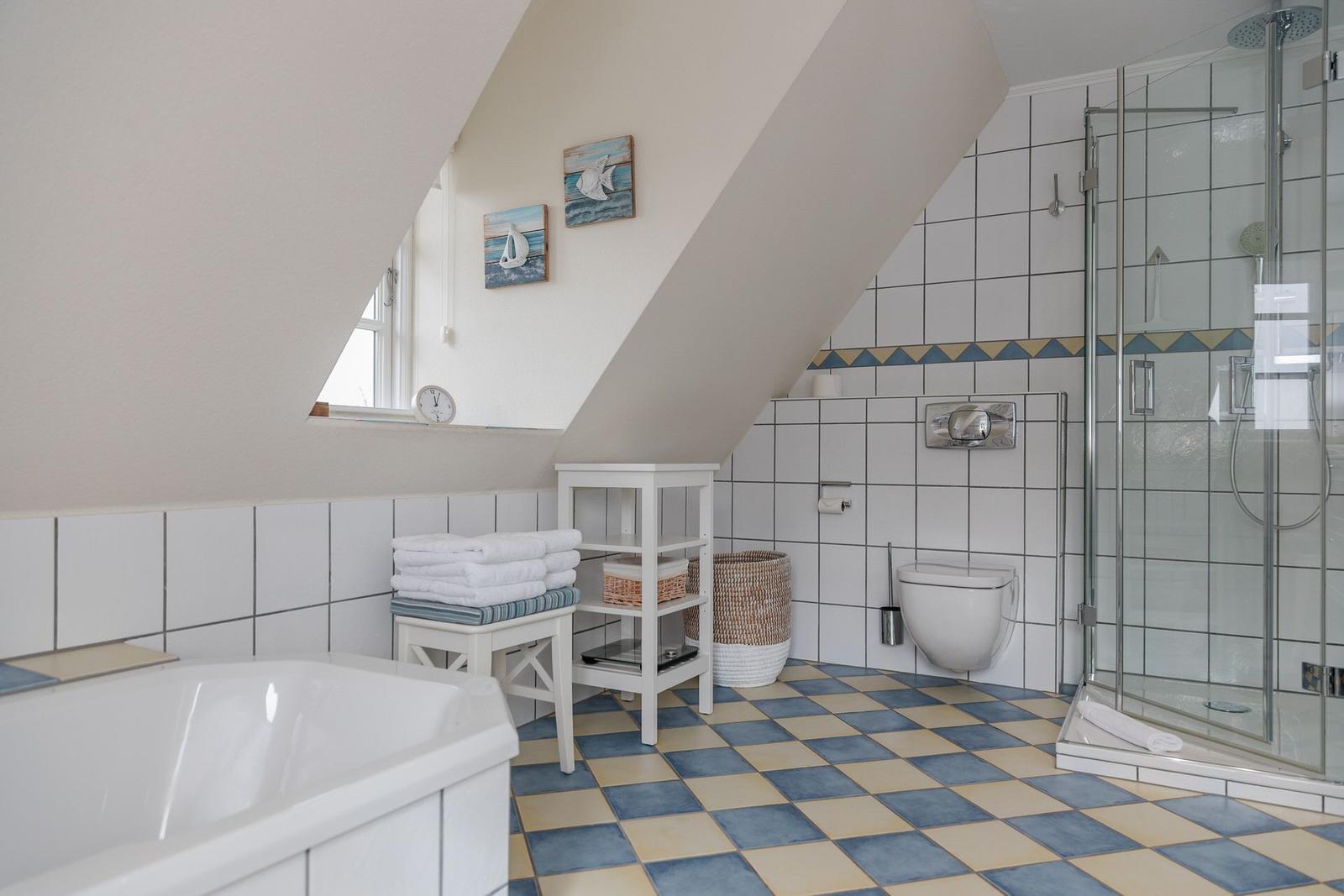 Badezimmer mit Dusche, WC, Badewanne und Fenster unter Dachschräge.