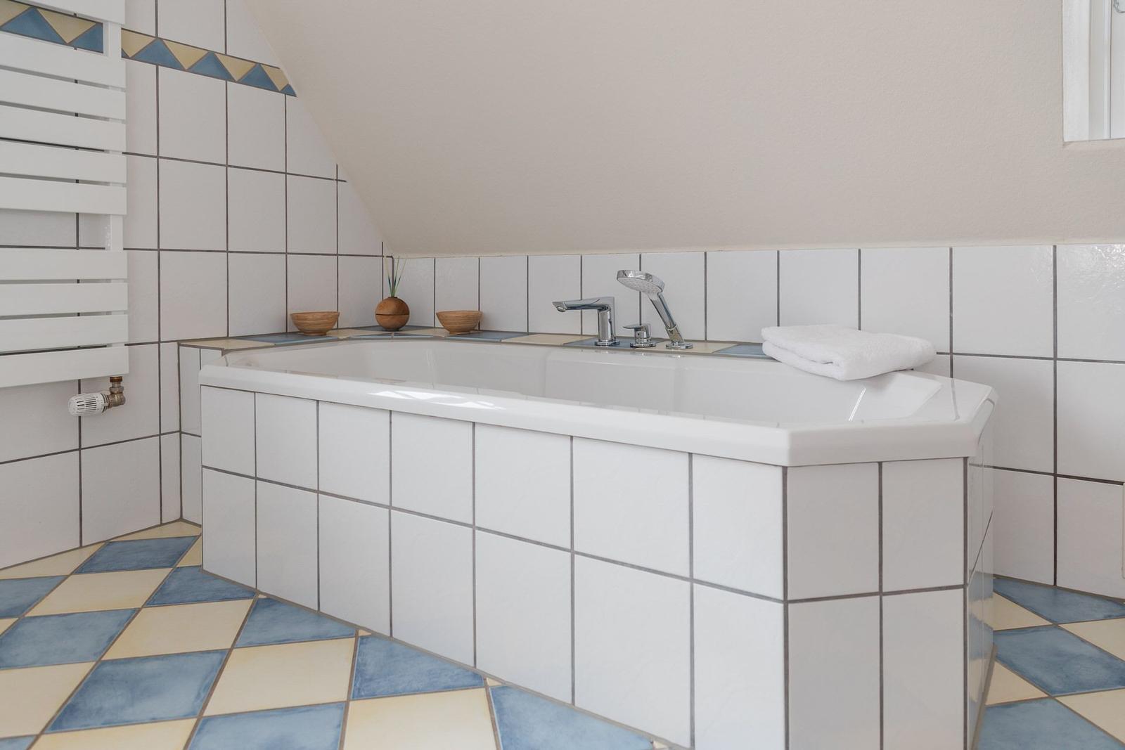 Badezimmer mit Dusche und Badewanne, gefliest mit blau-weißen Fliesen.