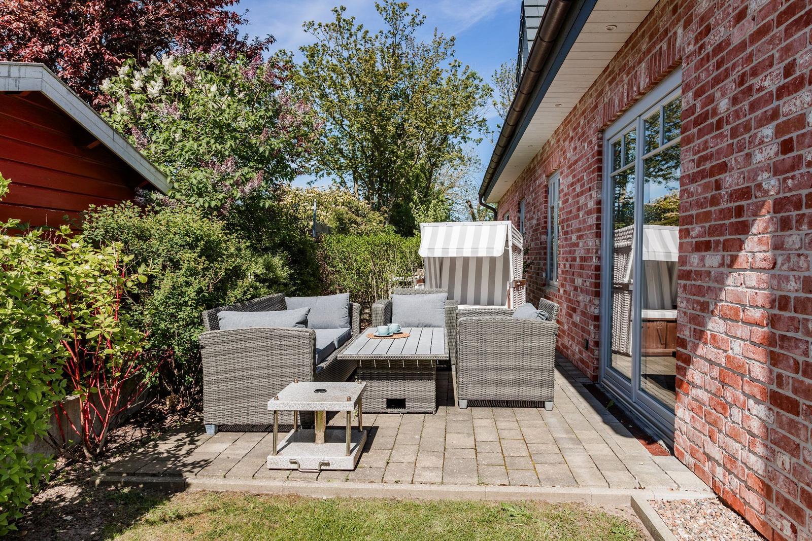 Terrasse mit Sitzgruppe, Sonnenschutz und Blick auf Garten.