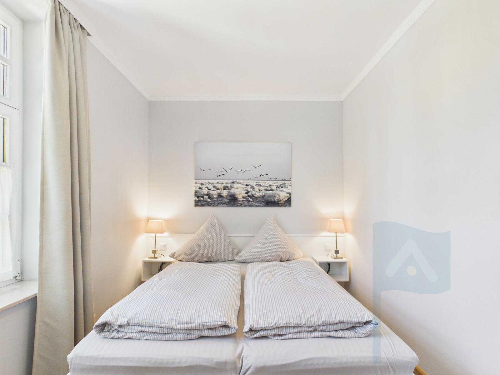 Ein Schlafzimmer mit Doppelbett, zwei Nachttischen und einer Wanddekoration.