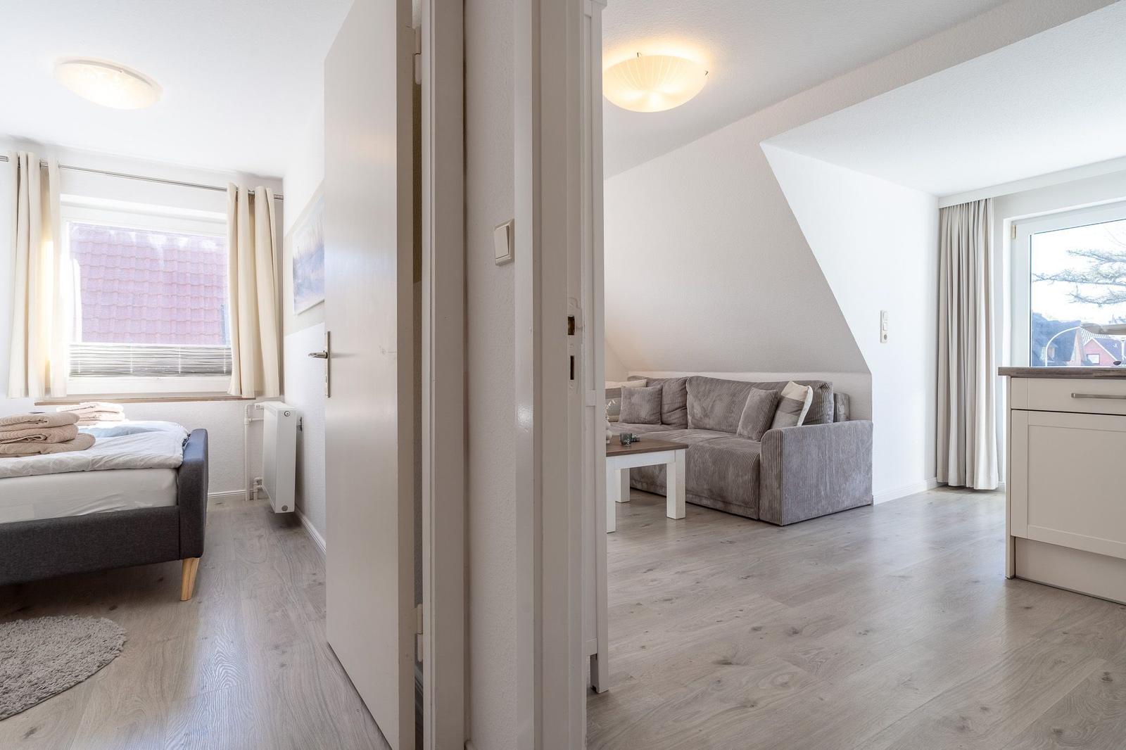 Schlafzimmer mit Bett und Fenster. Wohnzimmer mit Sofa und Tisch.