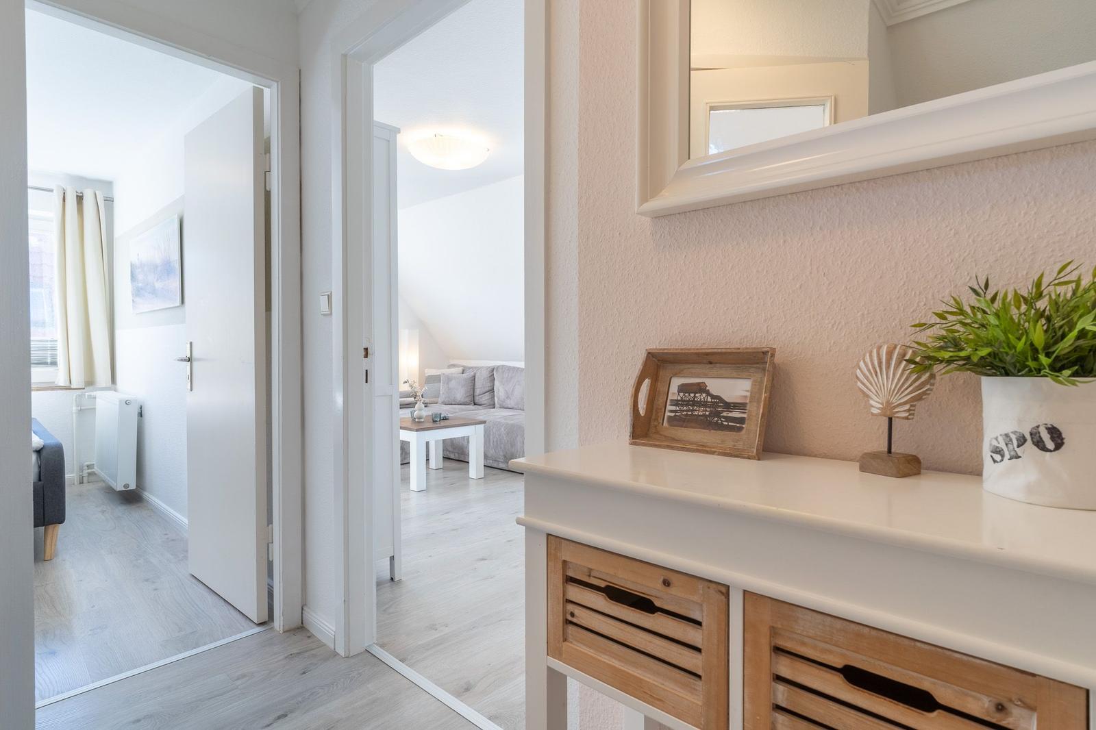 Eingangsbereich mit Schrank, Spiegel und Dekorationsgegenständen. Durchgänge zu Wohn- und Schlafzimmer.