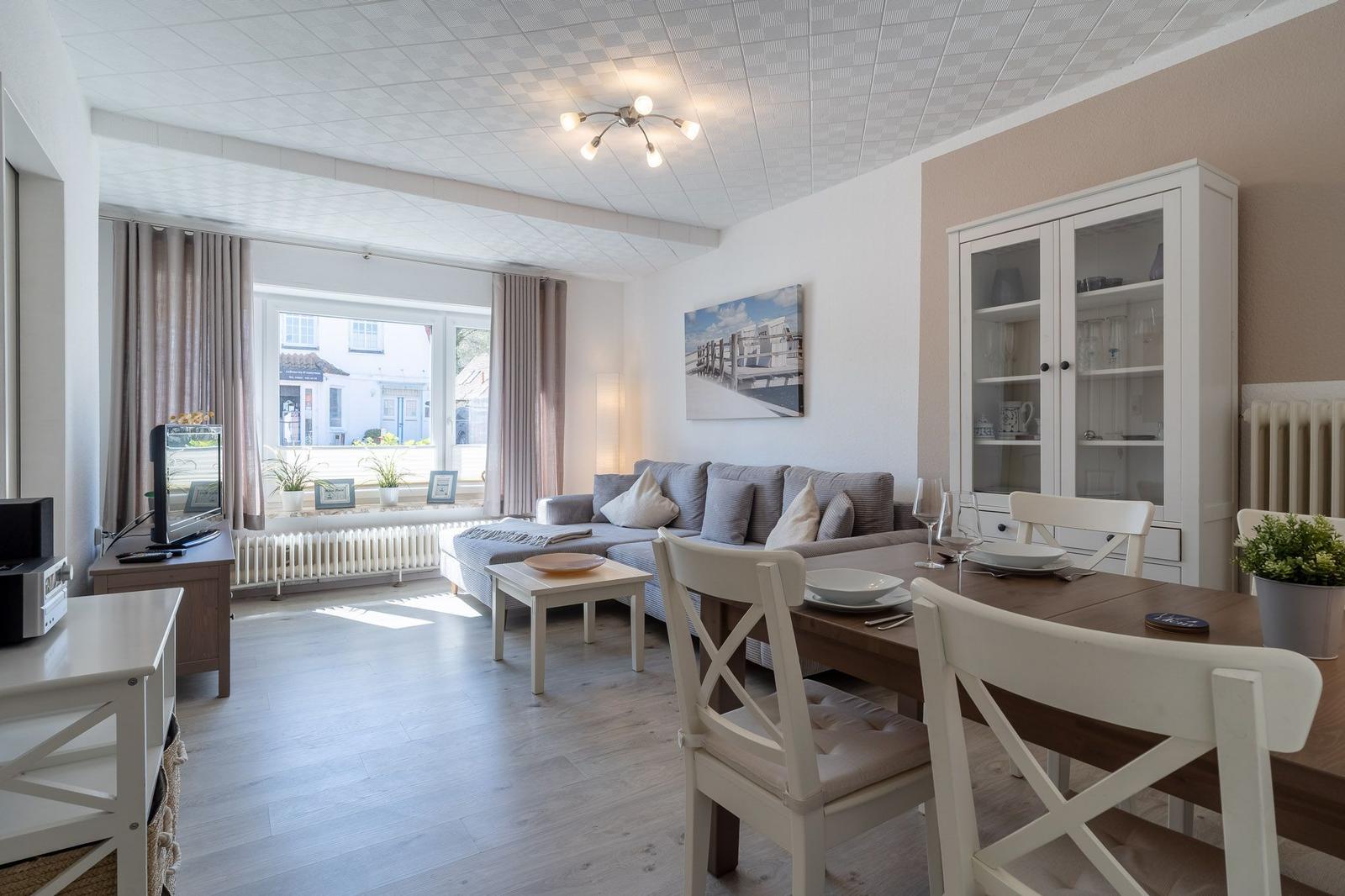 Wohn- und Essbereich mit Sofa, Esstisch und Glaswand-Schrank.