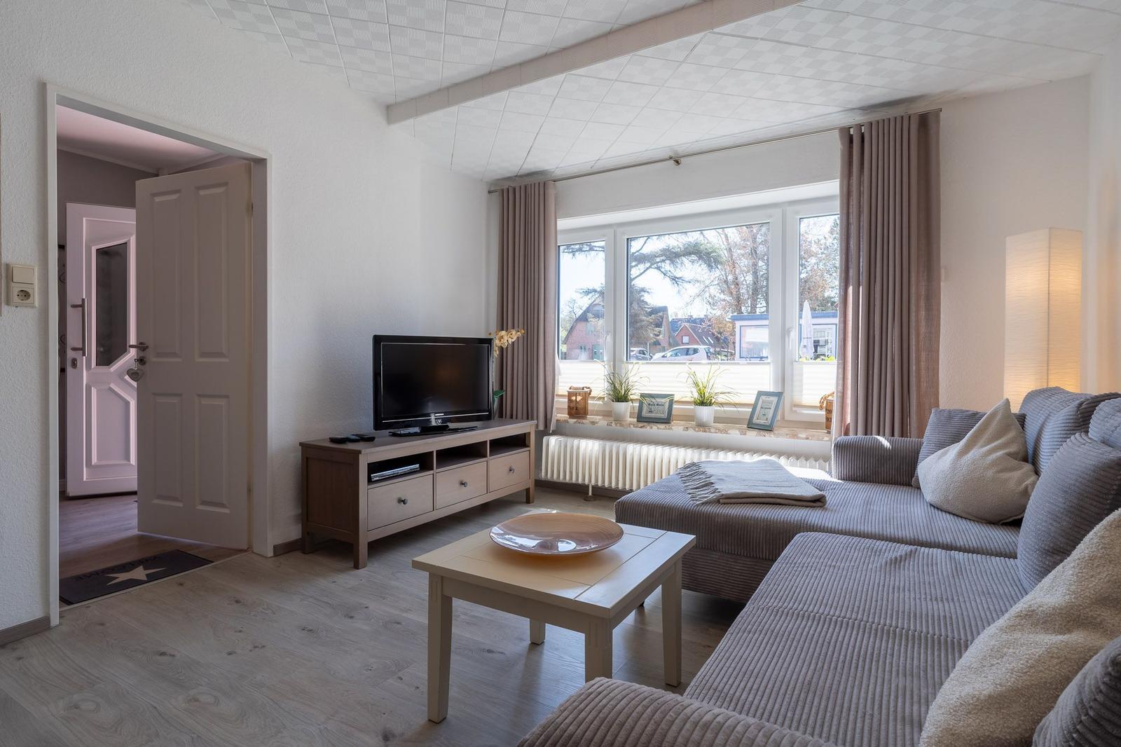Wohnzimmer mit Sofa, TV und Fenster mit Blick nach draußen.