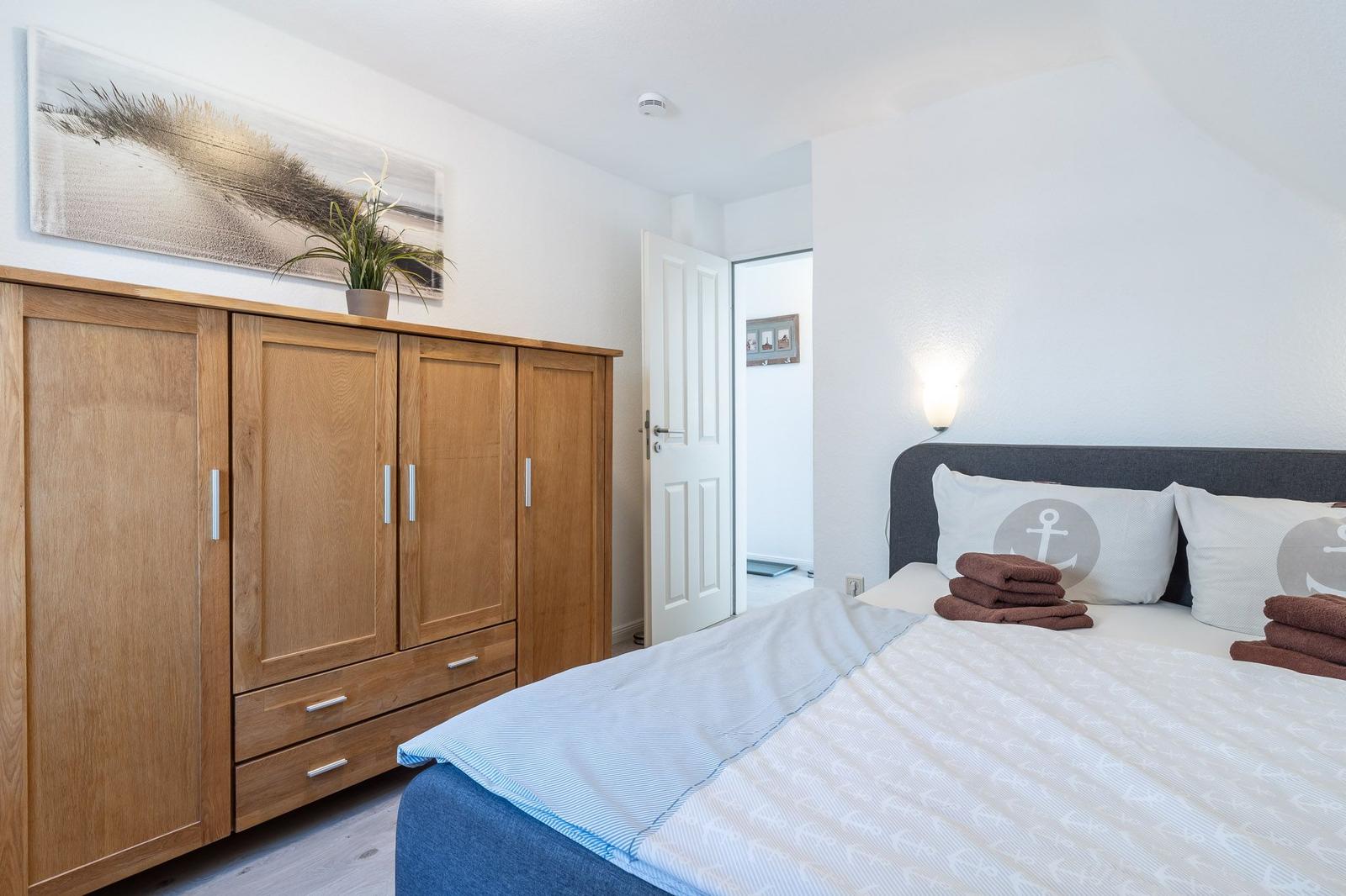Schlafzimmer mit Bett, Kleiderschrank und Wandbild.
