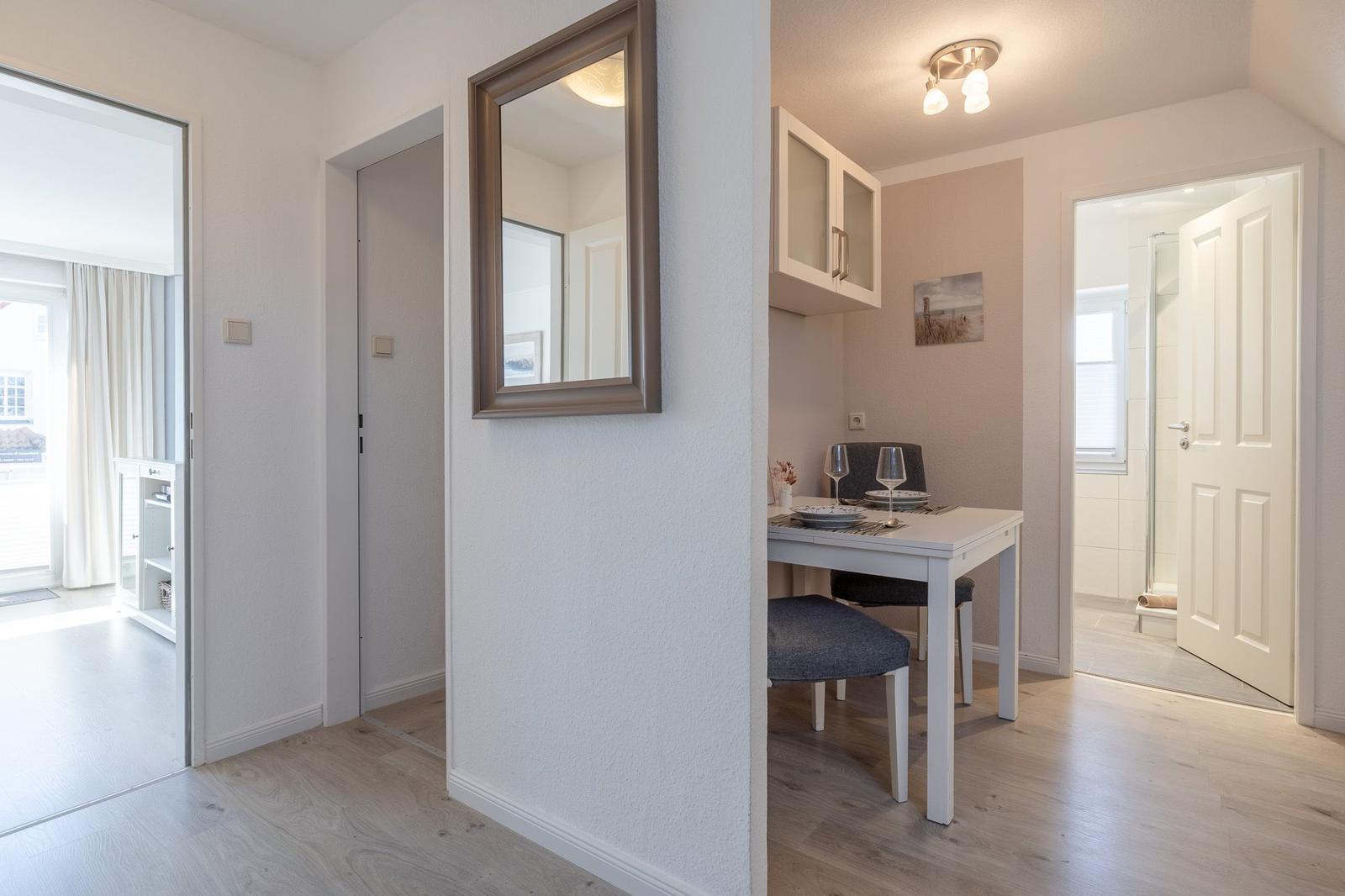 Essbereich mit Tisch, Stühlen und Küchenschränken. Blick in Schlaf- und Badezimmer.