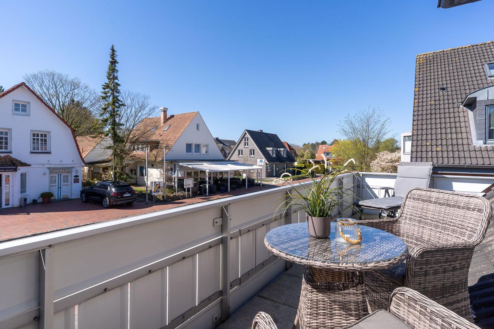 Terrasse mit Sitzgruppe und Tisch. Blick auf Wohnhäuser und Straße.