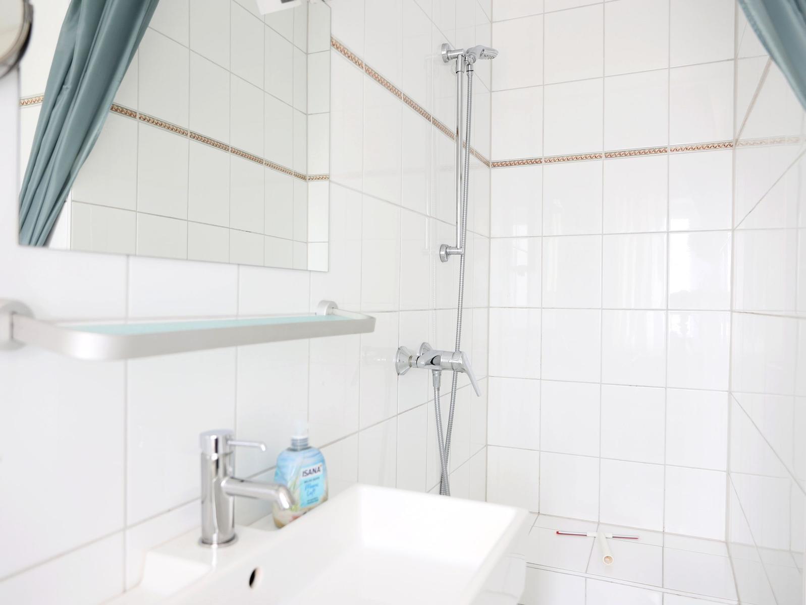 Badezimmer mit Dusche, Waschbecken und Spiegel