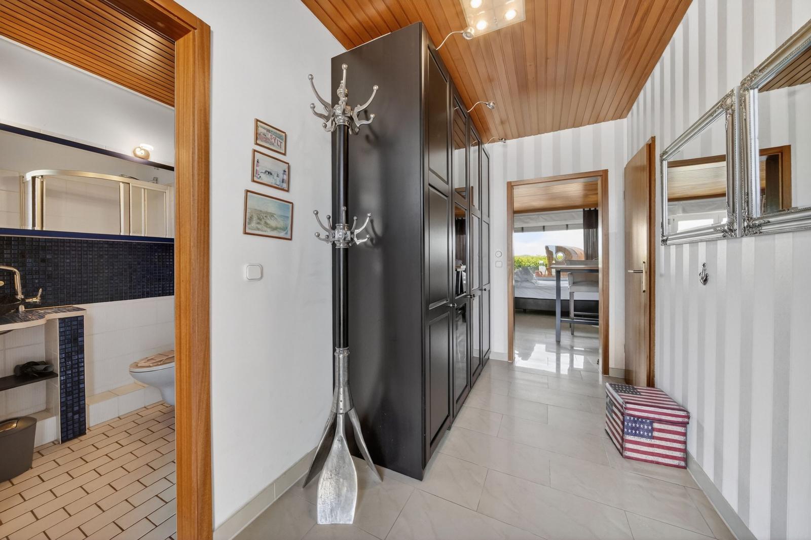Flur mit Garderobe, Spiegel und Blick in Schlafzimmer und Bad.