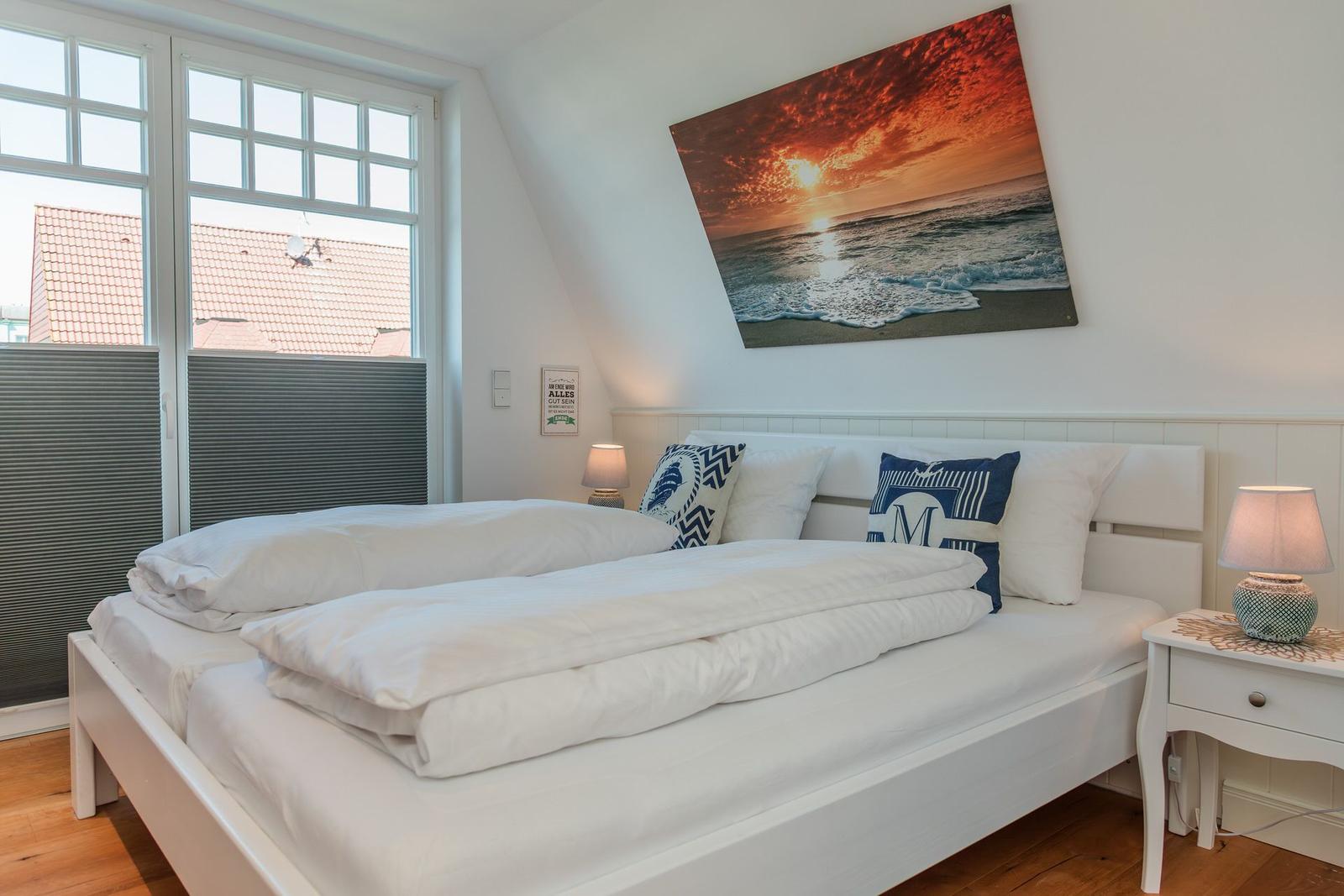 Schlafzimmer mit Doppelbett, Fenster und Wandbild.