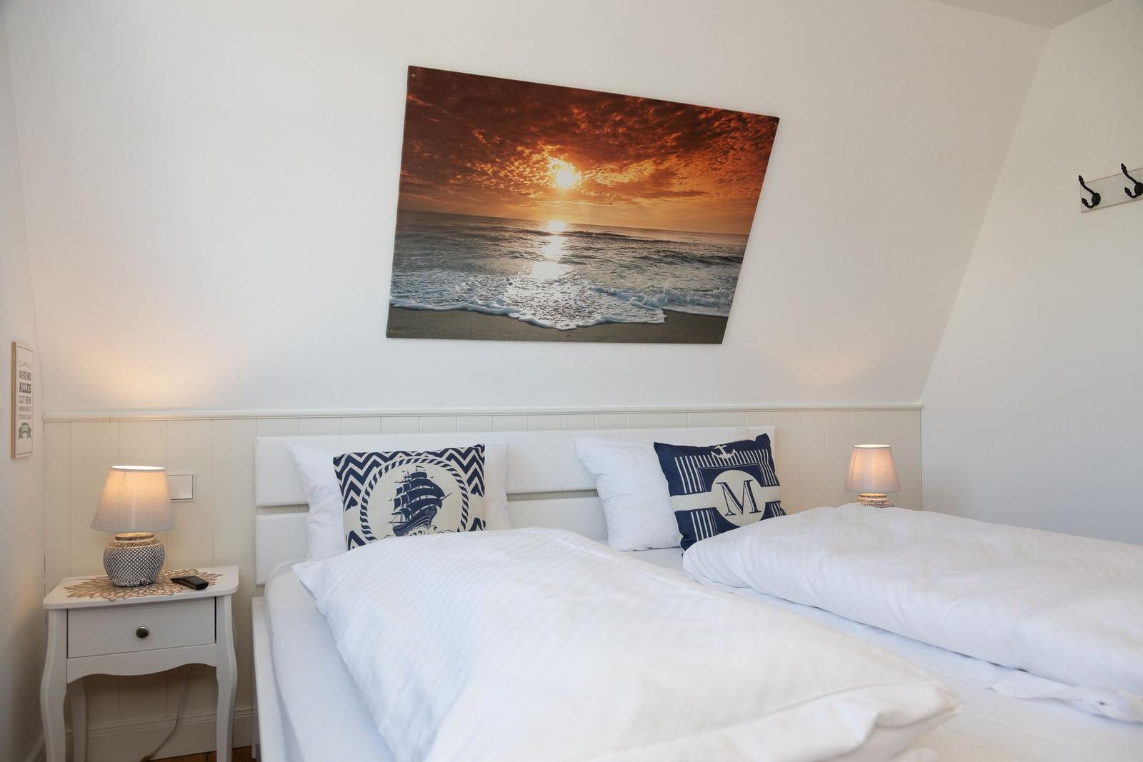 Schlafzimmer mit Doppelbett, Wandbild und Nachttisch mit Lampe.