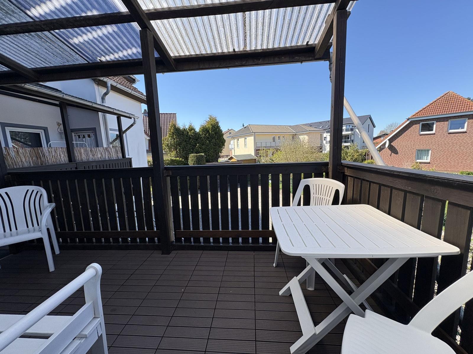 Terrasse mit weißem Tisch und Stühlen unter Dach