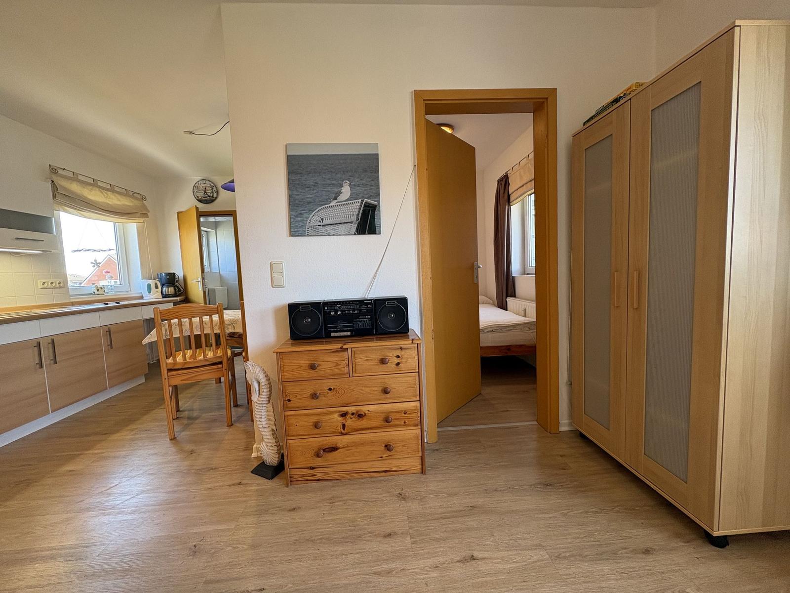 Wohnung mit Küchenbereich, Schlafzimmer und Holzmöbeln.