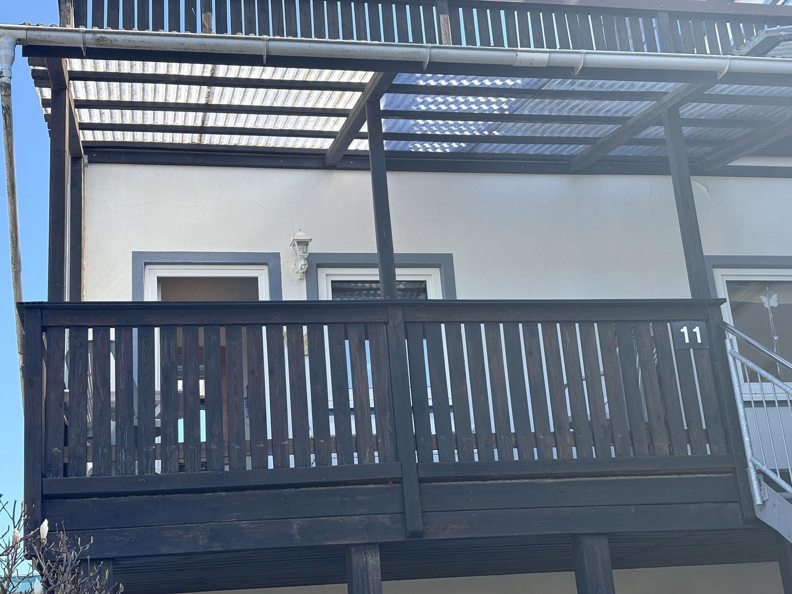 Terrasse mit Holzgeländer und Markise über dem Eingangsbereich