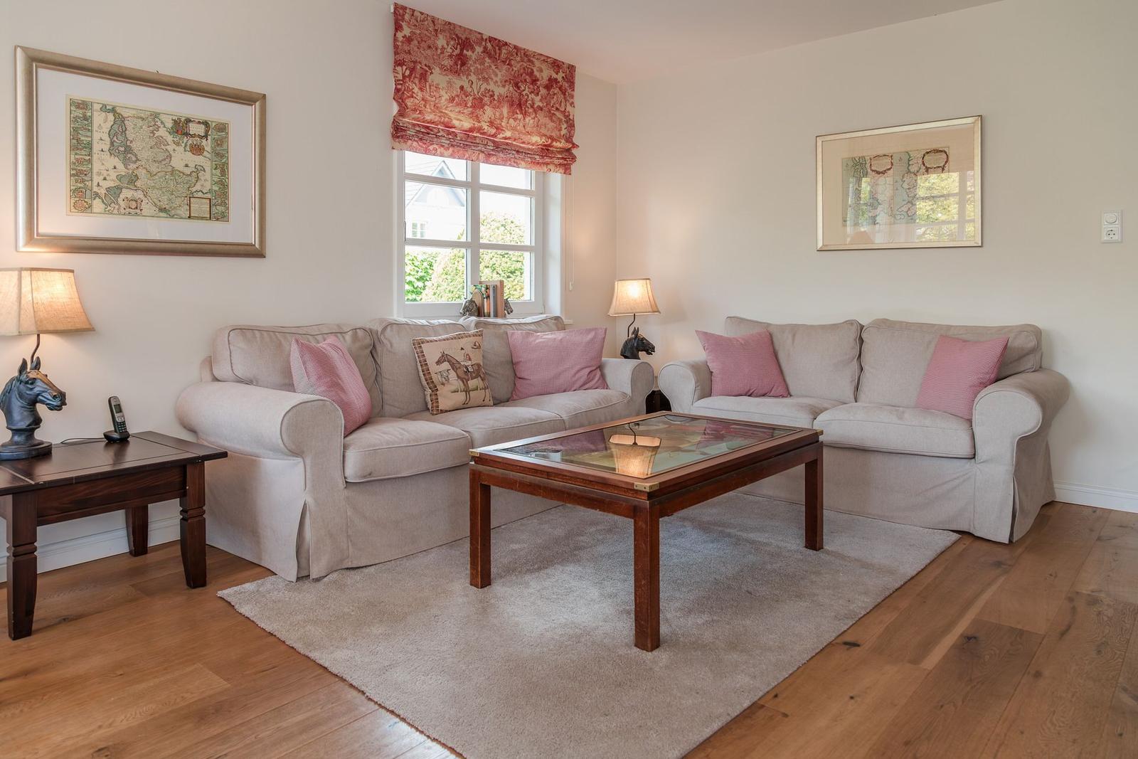 Wohnzimmer mit zwei Sofas, Glas-Tisch und Holzboden. Fenster mit rotem Rollladen.