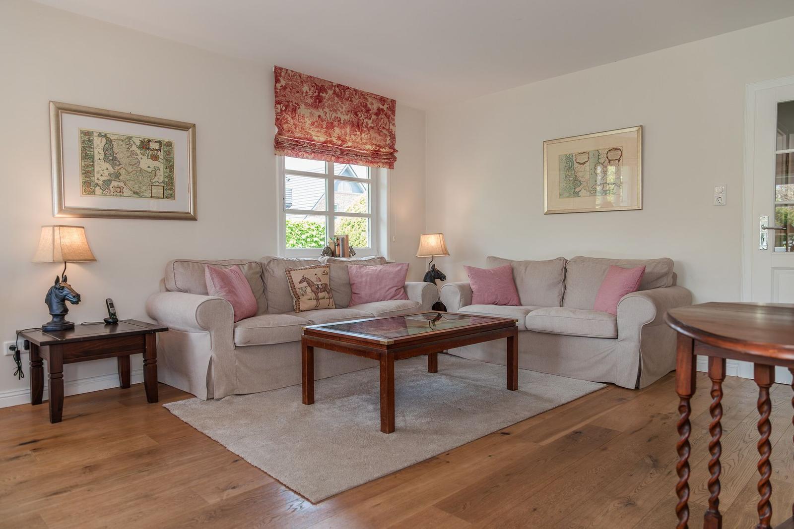 Wohnzimmer mit zwei Sofas, Glas-Tisch und Holzboden. Fenster mit rotem Rollladen.