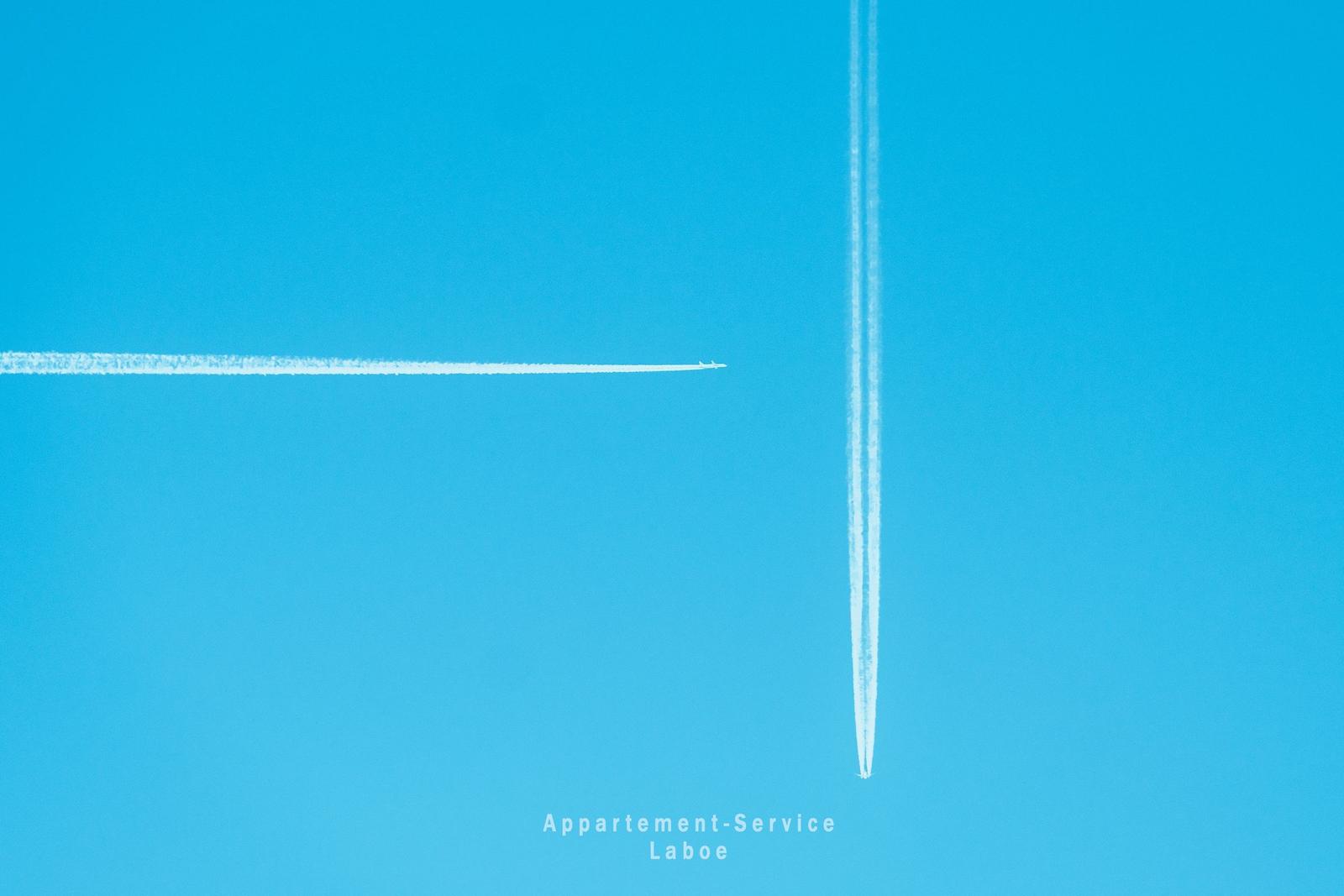 Zwei Flugzeuge hinterlassen weiße Spuren im blauen Himmel.