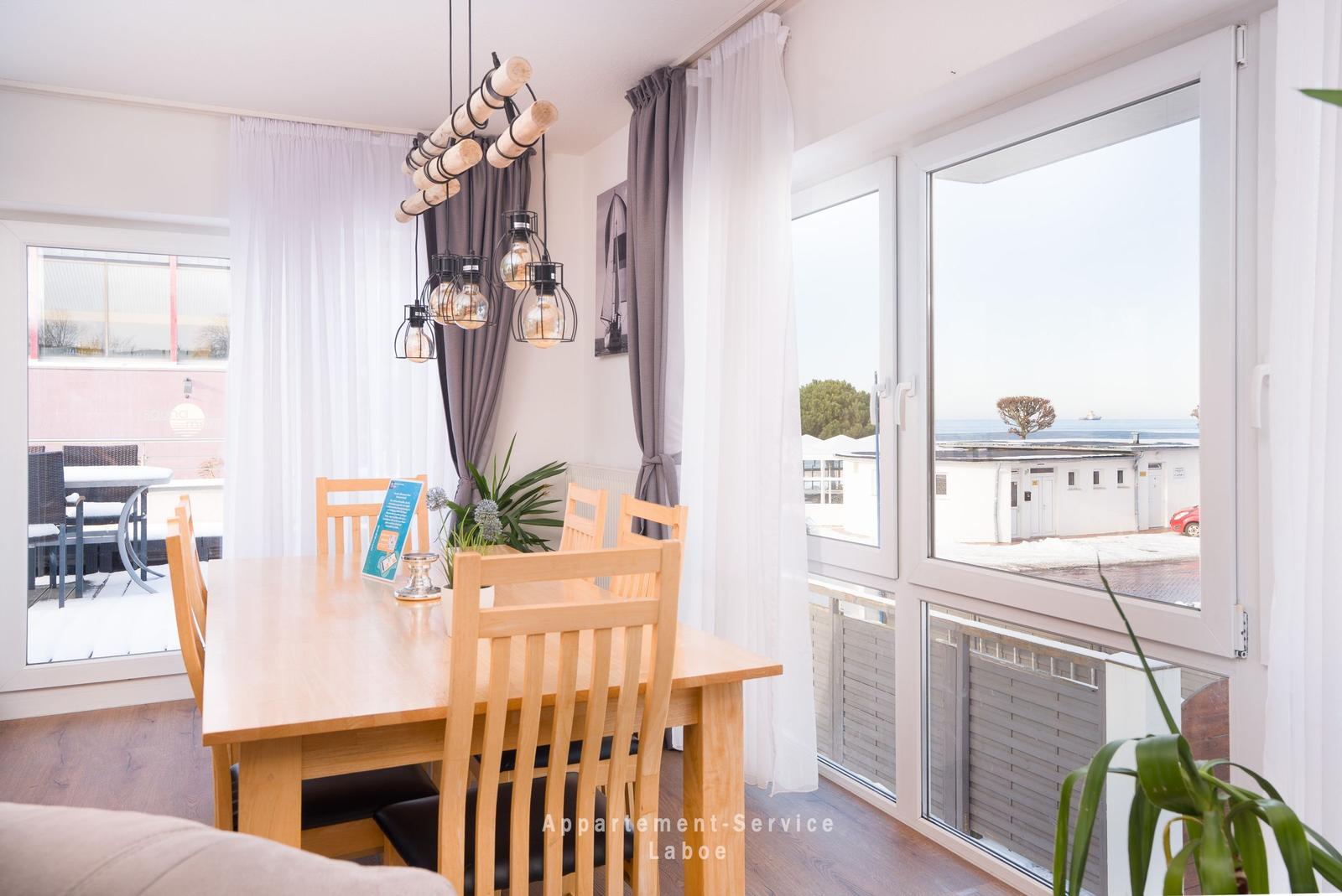Esszimmer mit Holztisch, Stühlen und Blick auf den Hafen.