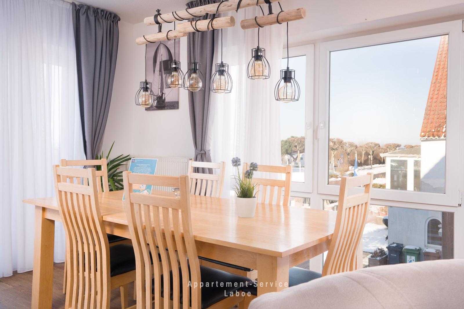 Esszimmer mit Holztisch, Stühlen und Fensterblick auf Außenbereich