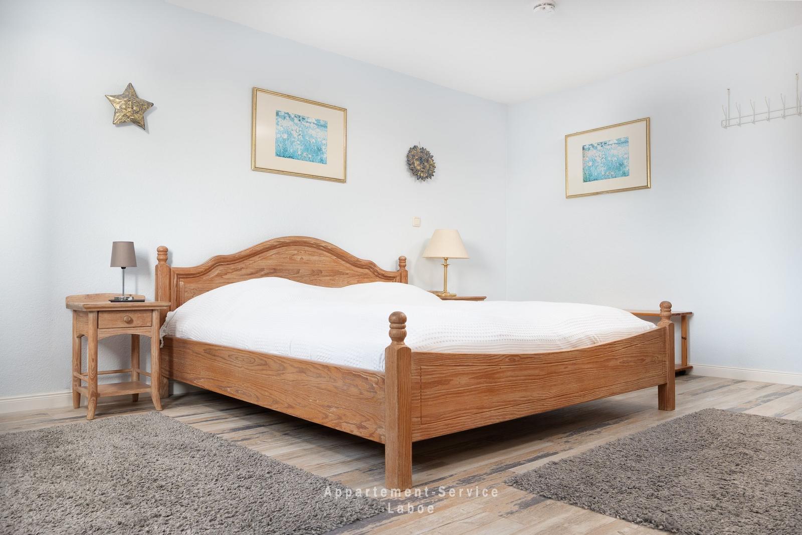 Schlafzimmer mit Holzbett, zwei Nachttischen und Wanddekoration.