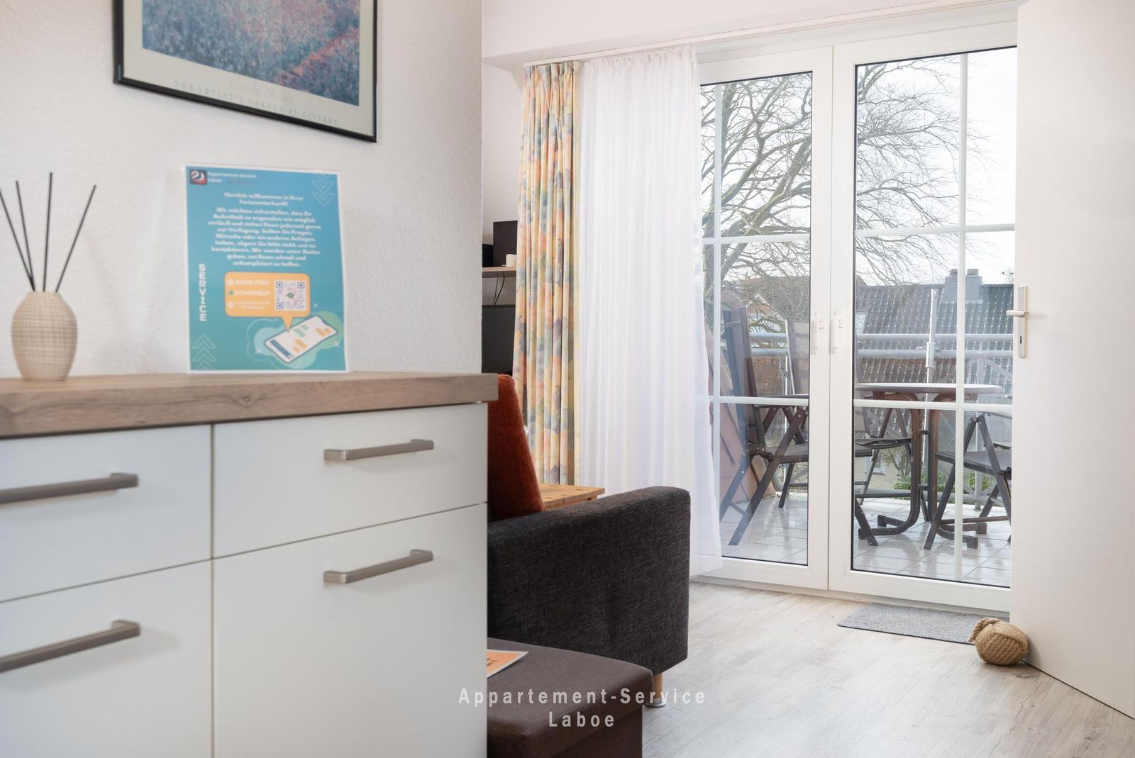 Wohnzimmer mit Blick auf Balkon, Schrank und Sessel