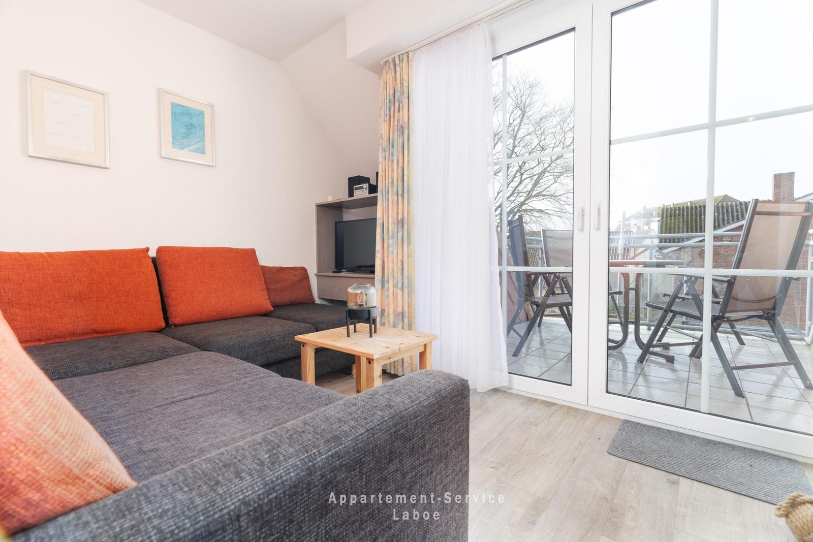 Wohnzimmer mit Sofa, Couchtisch und Terrasse mit Gartenmöbeln.