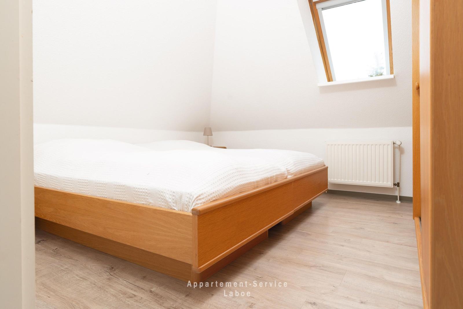 Schlafzimmer mit Doppelbett, Holzboden und Dachfenster.