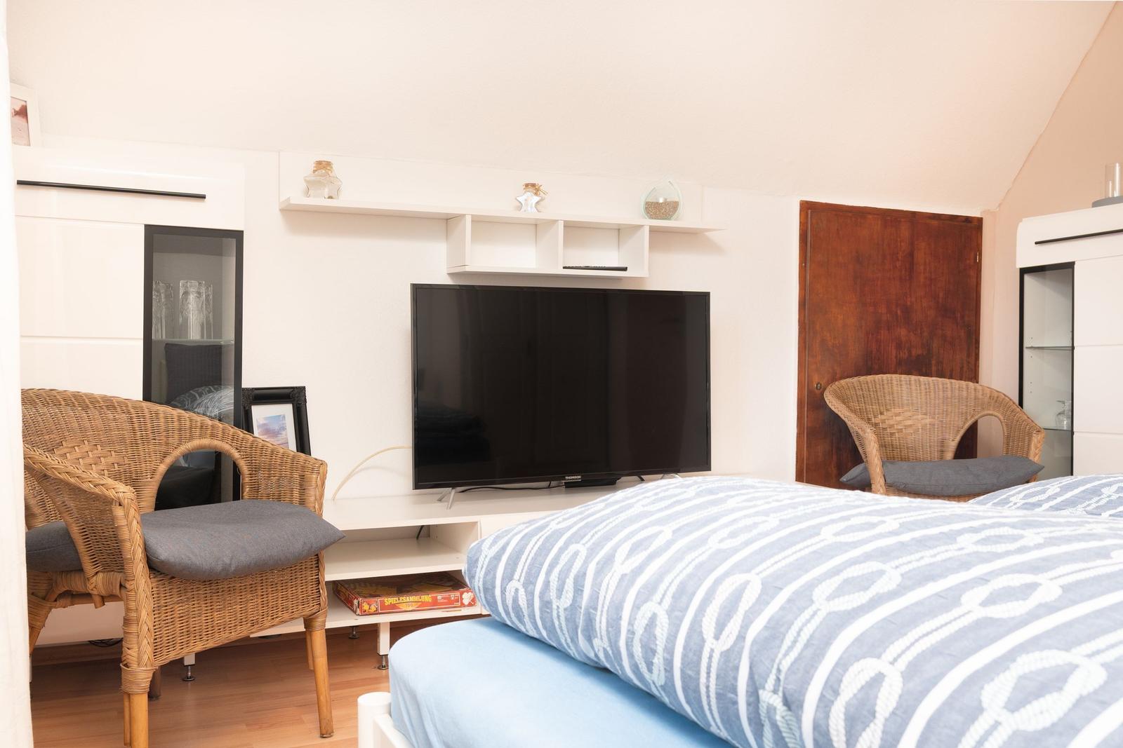 Ein Schlafzimmer mit Bett, Fernseher und zwei Stühlen.