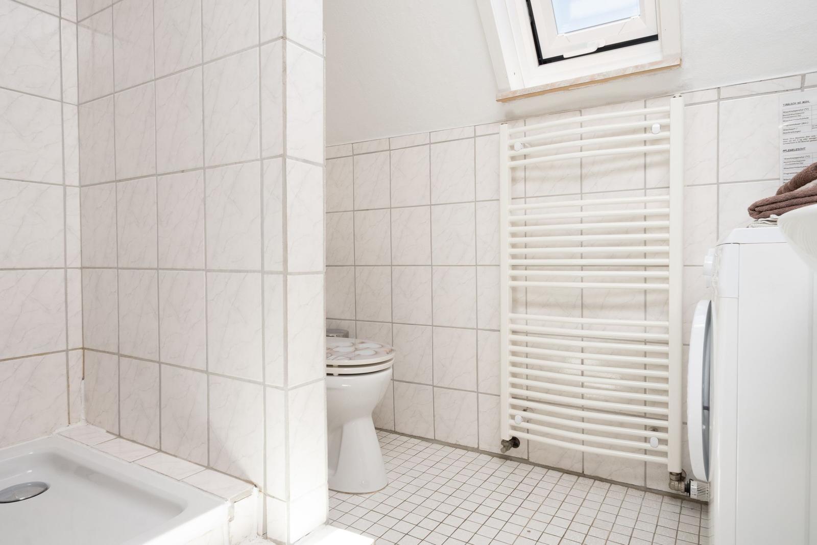 Bad mit Dusche, Toilette, Heizkörper und Waschmaschine.