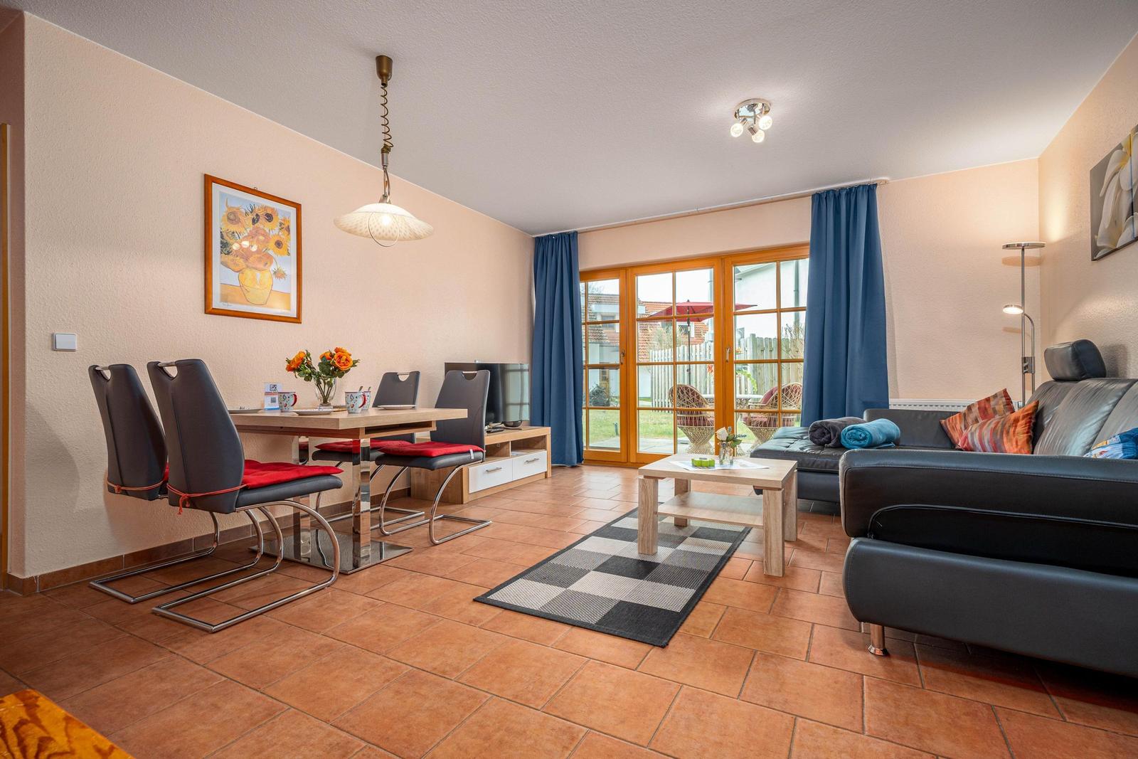 Wohn- und Essbereich mit Sofa, Tisch, Stühlen und Blick auf den Garten.
