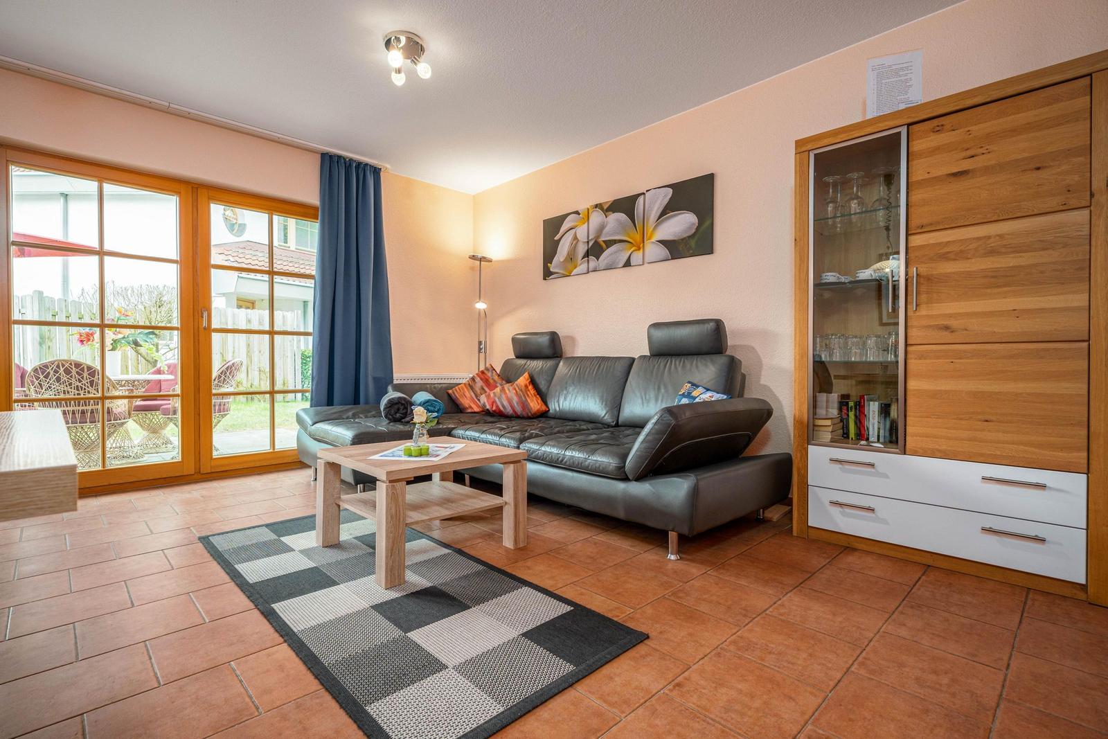 Wohnzimmer mit Ledersofa, Holztisch und Glastür zur Terrasse.