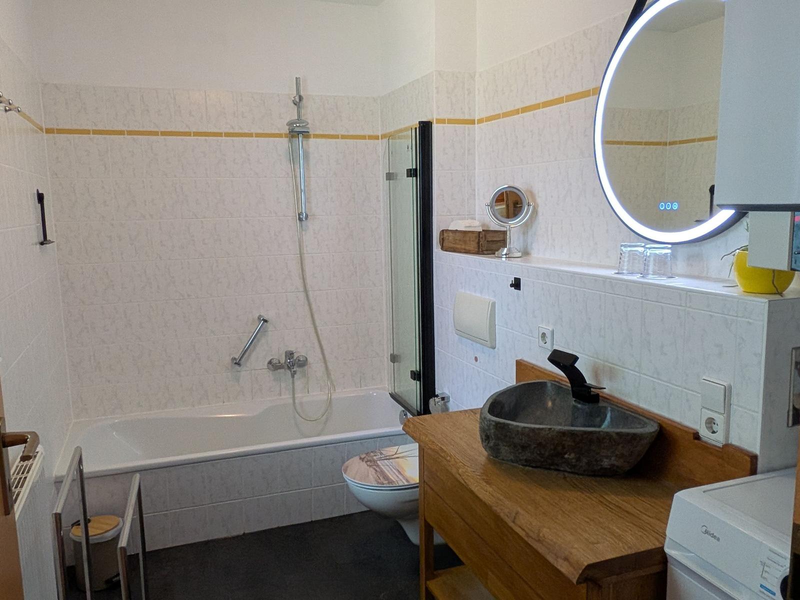 Badezimmer mit Badewanne, Dusche, Waschbecken und Spiegel.