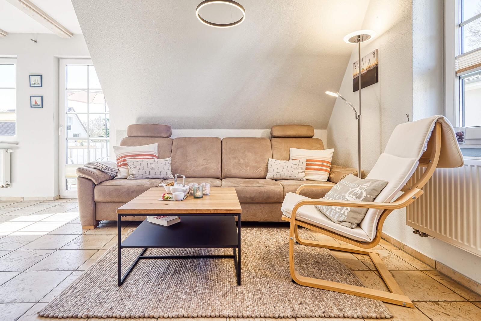 Wohnzimmer mit Sofa, Sessel, Tisch und Teppich unter einem schrägen Dach.
