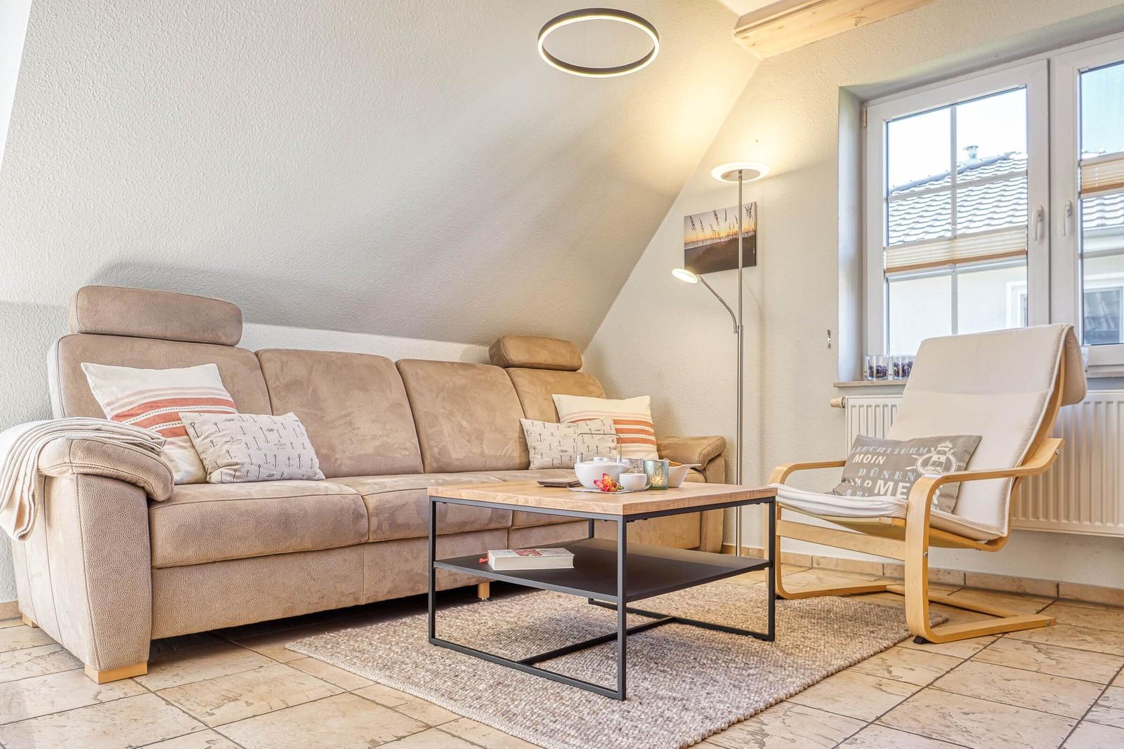 Wohnzimmer mit Sofa, Sessel und Tisch unter schrägem Dach