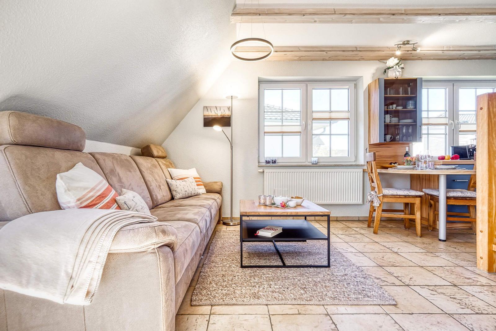 Wohn- und Essbereich mit Sofa, Couchtisch und Essplatz unter Holzbalkendecke.
