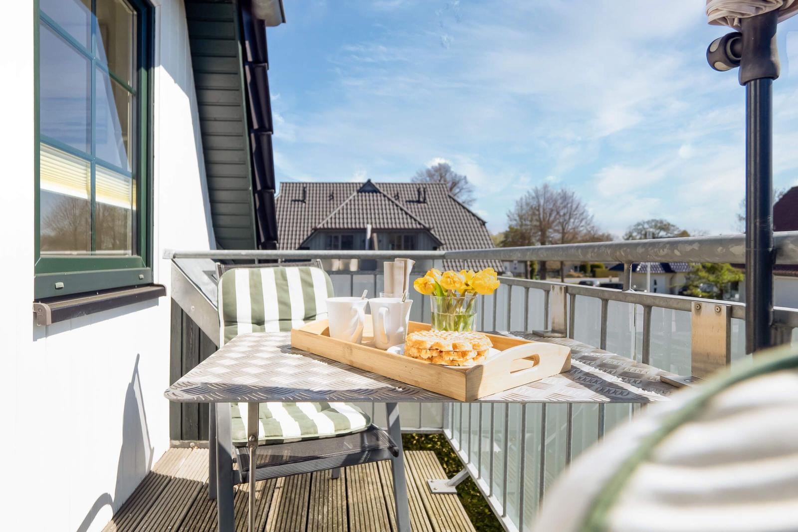 Terrasse mit Tisch, Stuhl und Frühstück. Blick auf Haus und Himmel.