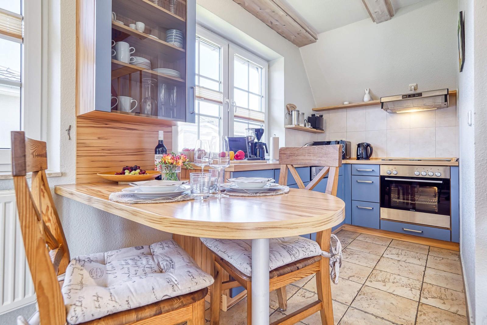 Küche mit Essbereich, Holztisch, Stühle und blauen Schränken.