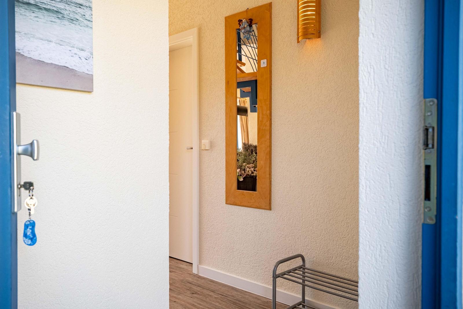 Eingangsbereich mit Spiegel, Wandbeleuchtung und Bild an der Wand.