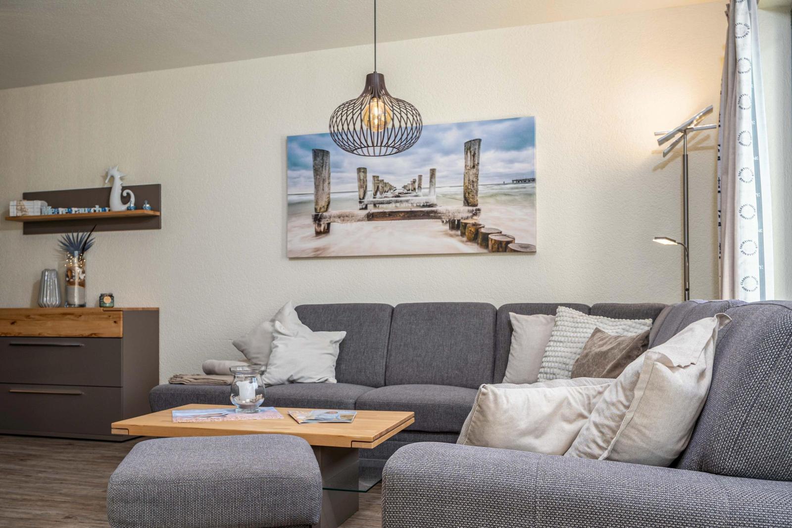 Ein Wohnzimmer mit grauem Sofa, Holztisch und Wandbild an der Wand.