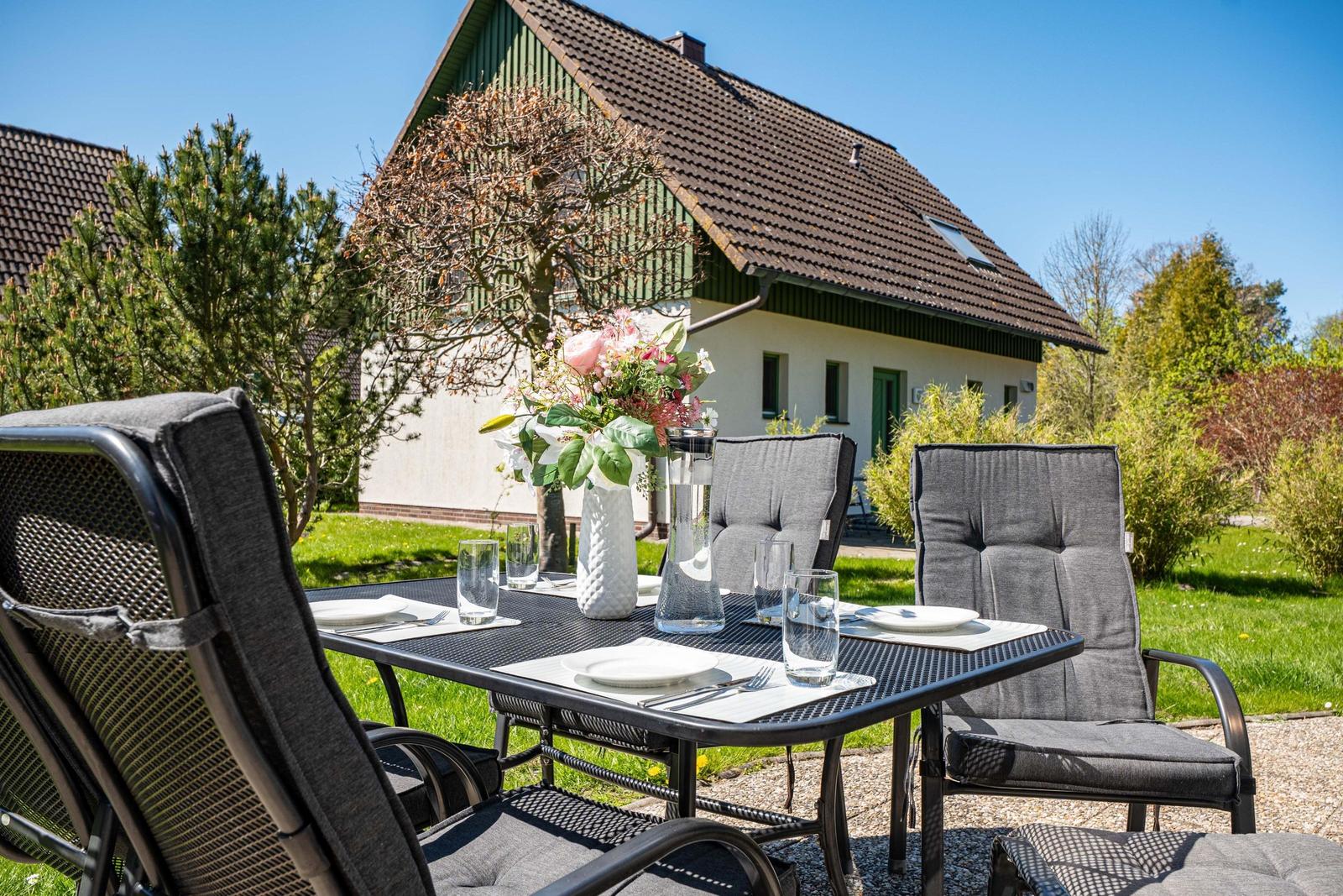 Terrasse mit Tisch und Stühlen vor einem Haus mit Garten.