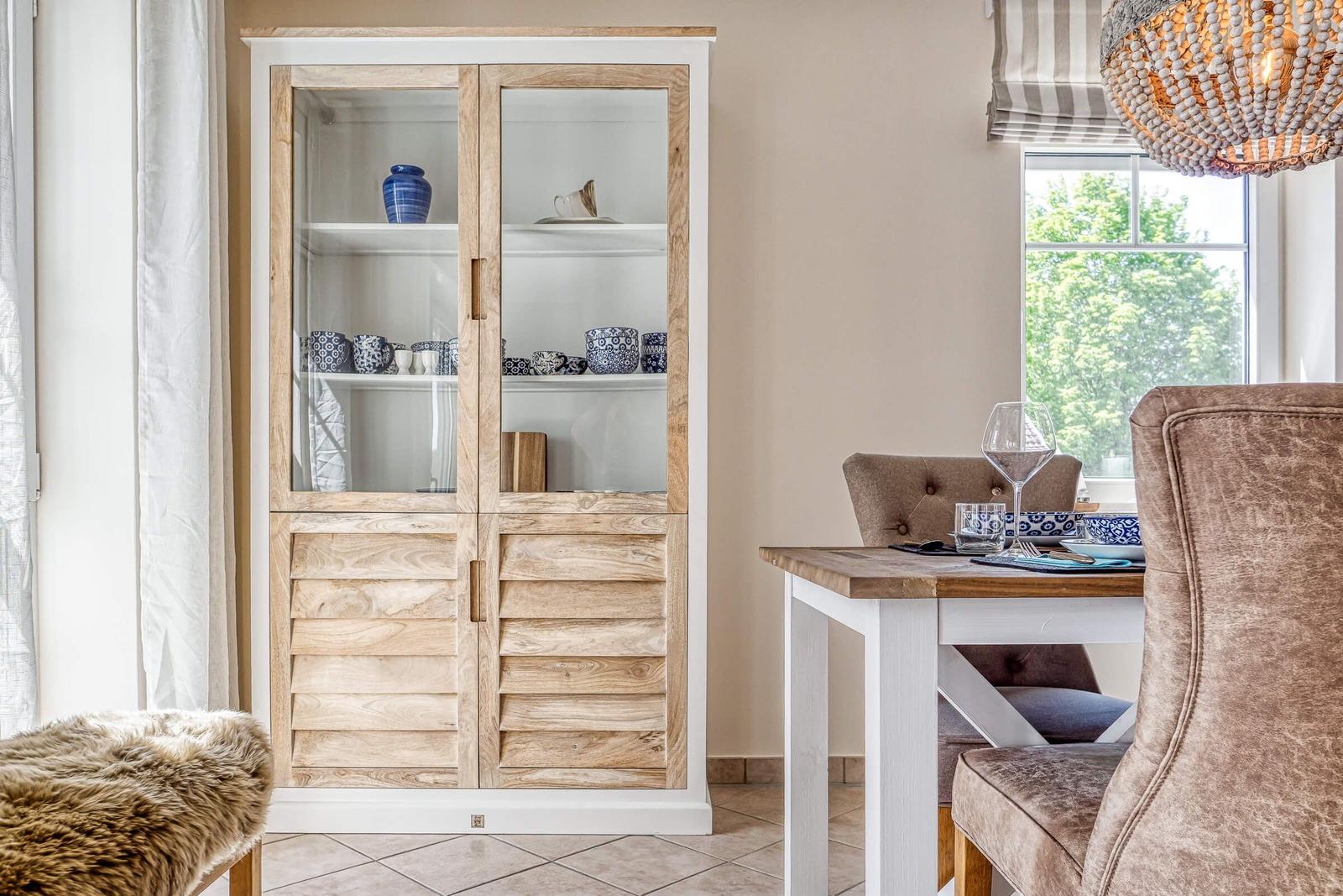 Esszimmer mit Holztisch, Stühlen und Schrank mit Geschirr.