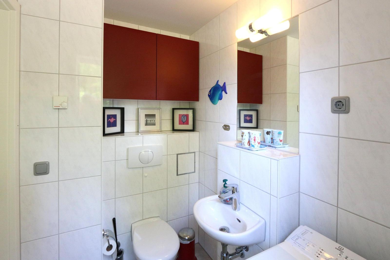 Badezimmer mit Toilette, Waschbecken und rotem Schrank.