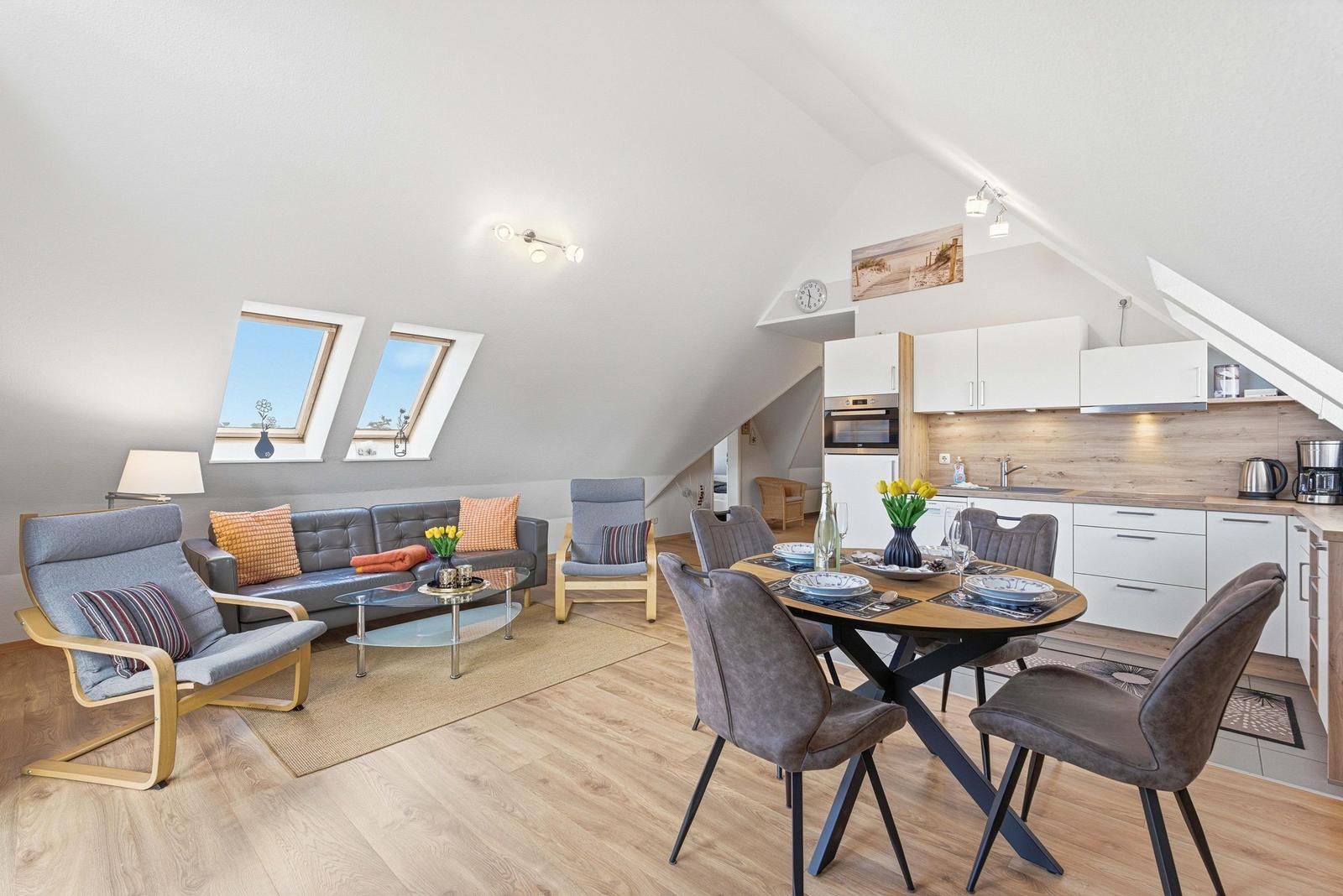 Wohn- und Essbereich mit Küche unter Dachschräge, zwei Dachfenster, Esstisch mit vier Stühlen.